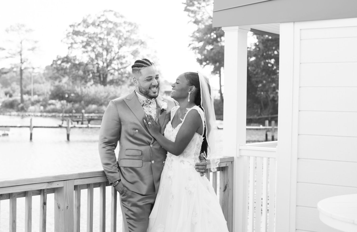 A romantic black and white photo of a couple sharing a joyful moment together on an outdoor porch.