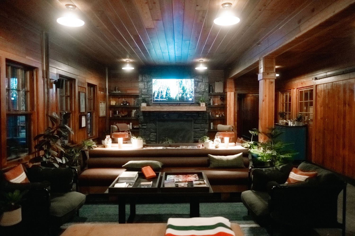 Warm glowing lights illuminate a cozy wood-paneled spa room with massage tables and luxurious treatment areas.