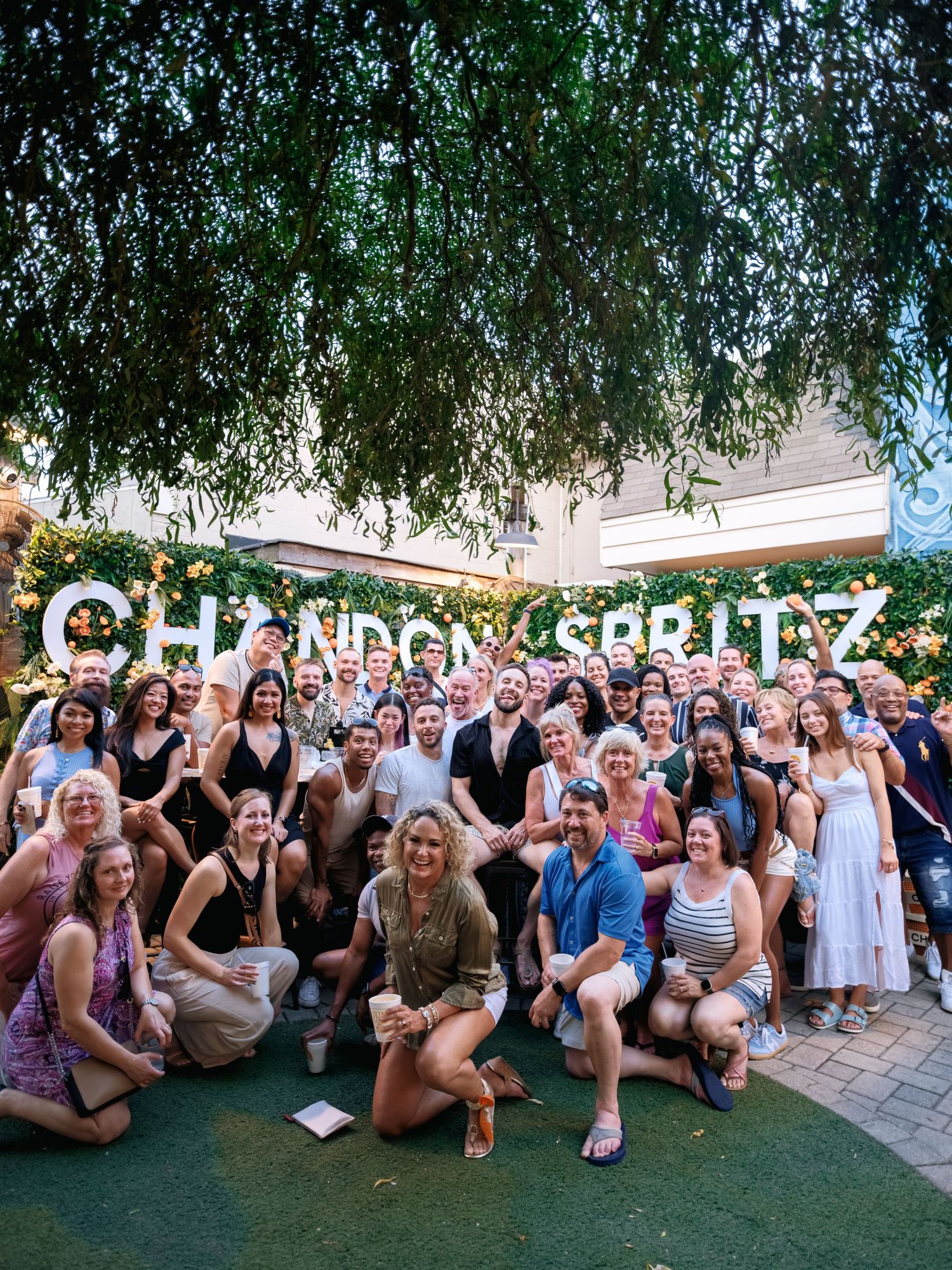 A large group gathers outdoors in front of illuminated 'CHOP AND SCALLZ' signage for a celebratory photo.