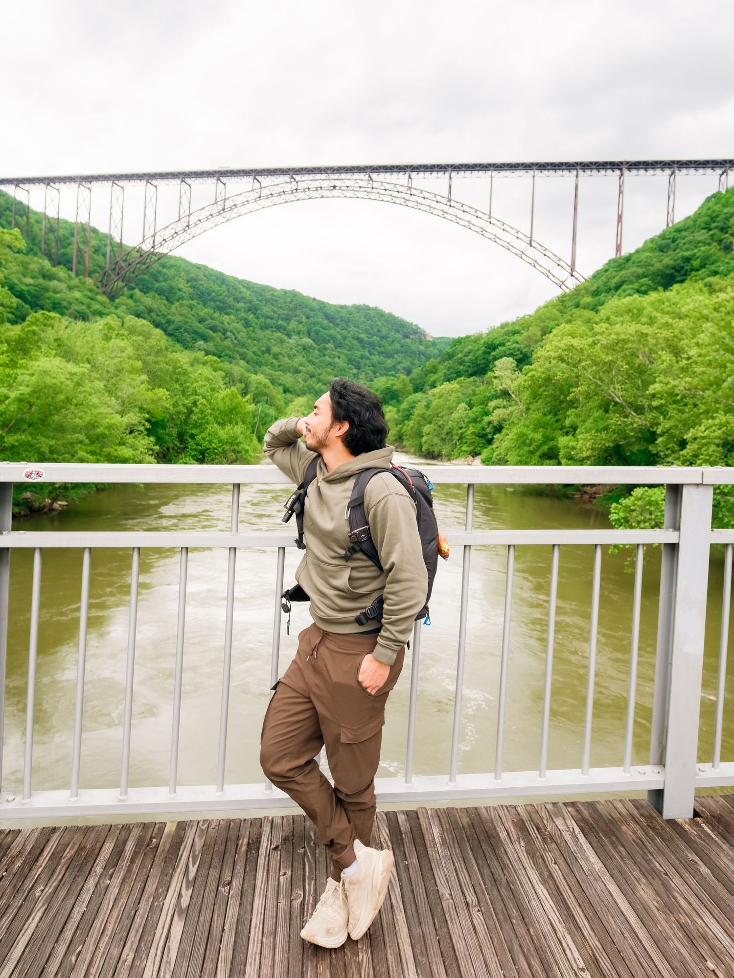 A scenic view of the New River Gorge Bridge in West Virginia with someone drinking water on the observation deck.