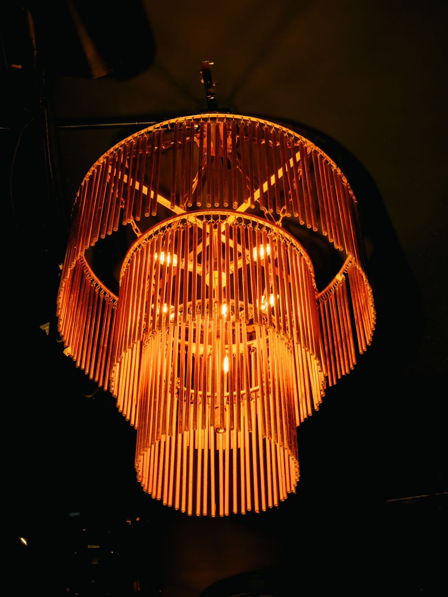 Sequence showing a glowing bamboo chandelier with warm orange light gradually transforming into different shapes and patterns.
