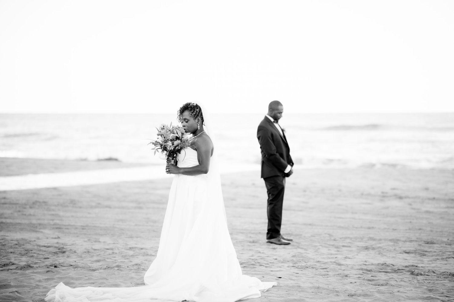Romantic beach wedding photo shoot with couple walking along the shoreline at sunset.