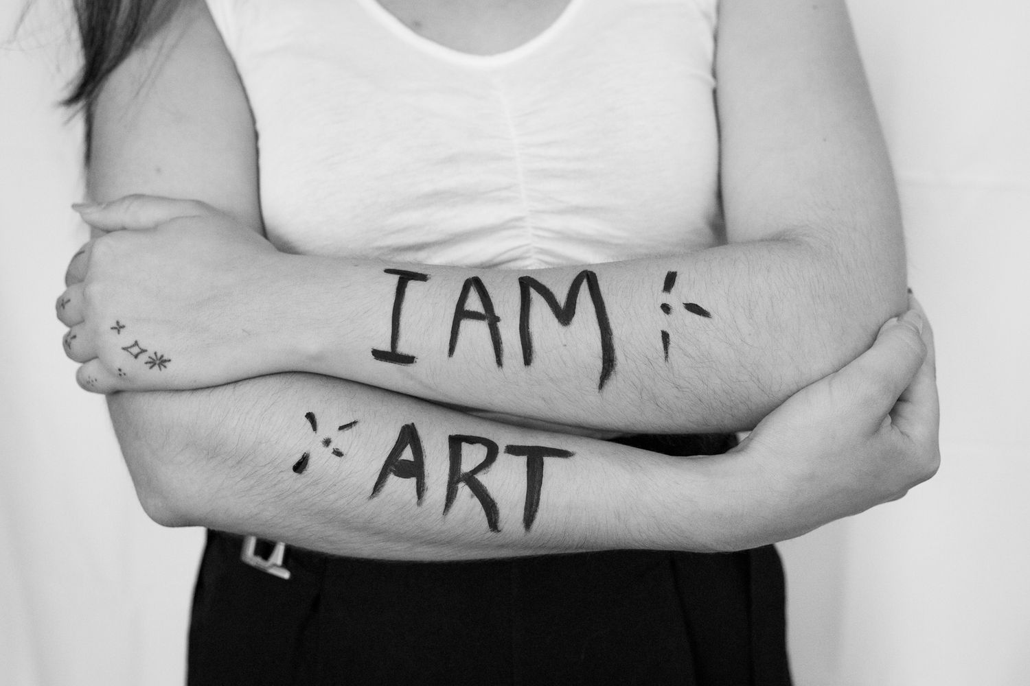 Black and white close-up of arms with 'I AM ART' written on skin.