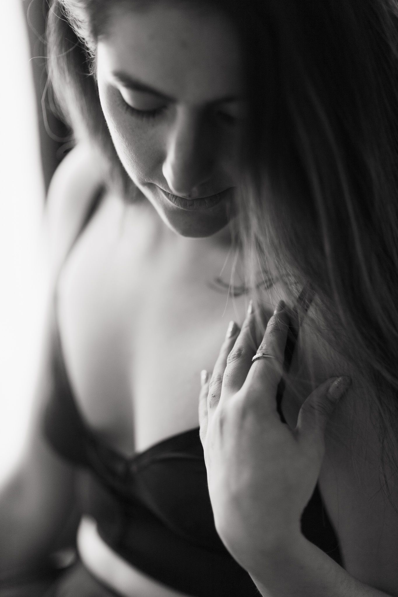 Intimate black and white portrait showing delicate hand placement and soft lighting.