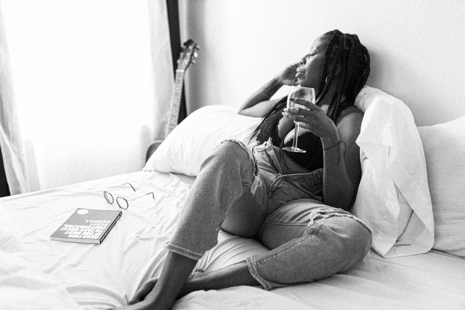Black and white image of relaxed person lounging on bed wearing comfortable clothes.