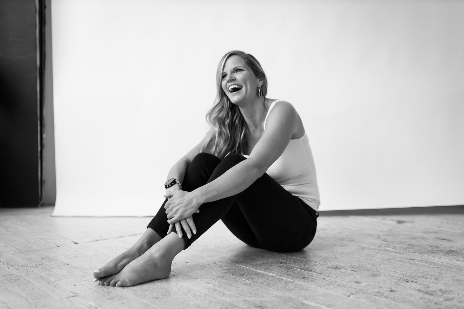 Candid black and white photo of someone laughing while sitting on the floor.