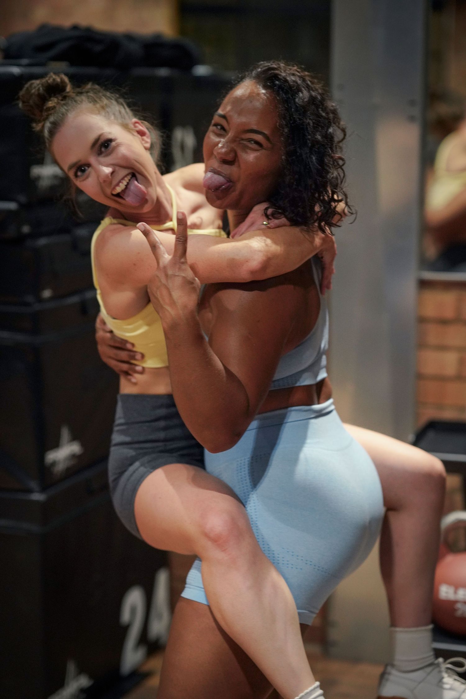 Two athletes in workout attire embrace and celebrate during an intense training session at the gym.