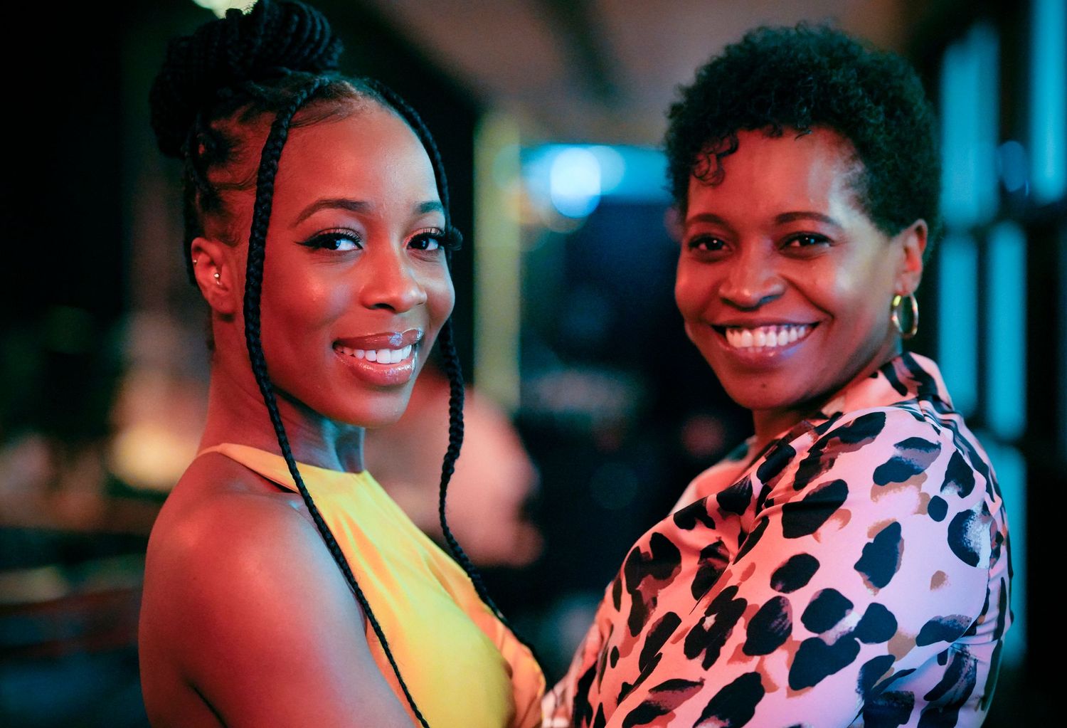 Two smiling people enjoying a night out together, one wearing yellow and one in leopard print.