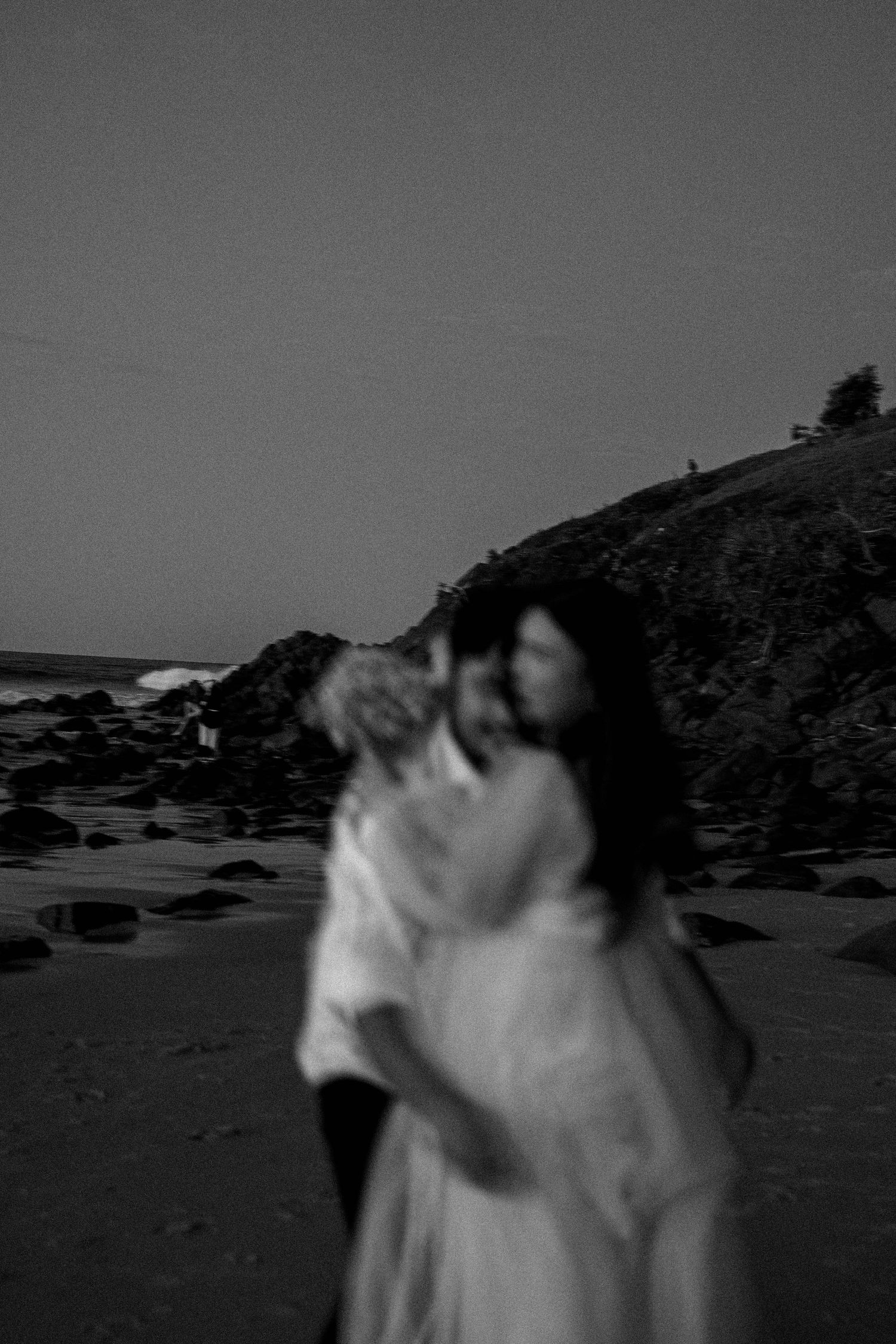 A series of black and white photographs showing a rocky beach landscape at sunset with silhouetted hills in the background.