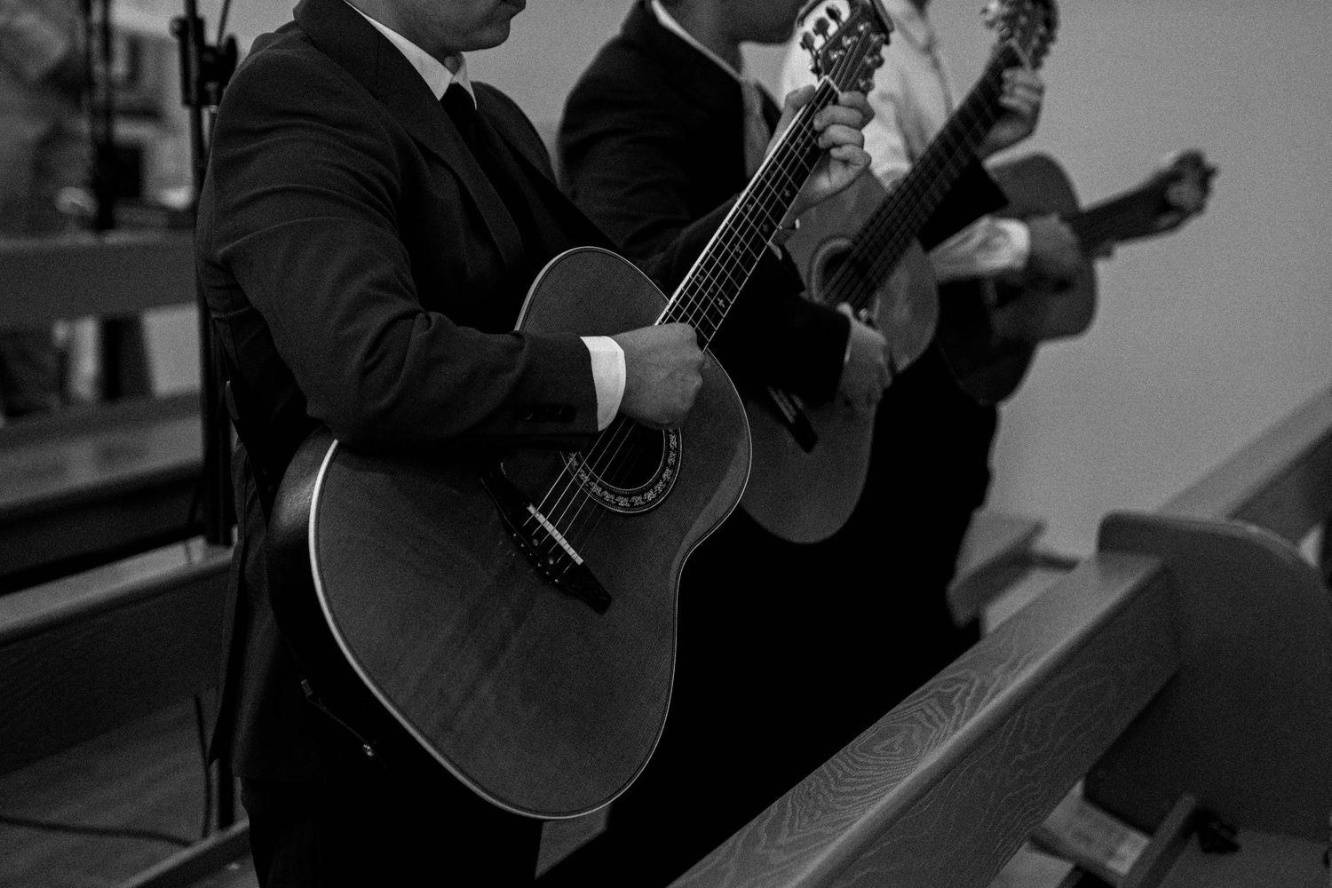 Black and white image of a person playing an acoustic guitar while performing on stage in a concert setting.