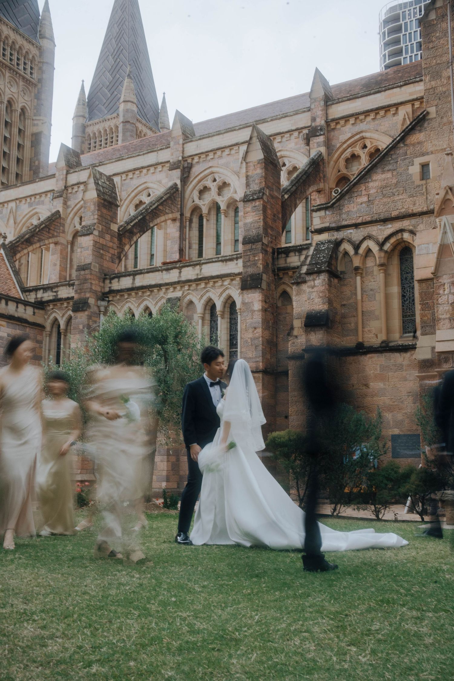 Motion blur sequence of a wedding couple dancing on the lawn outside a historic Gothic cathedral.