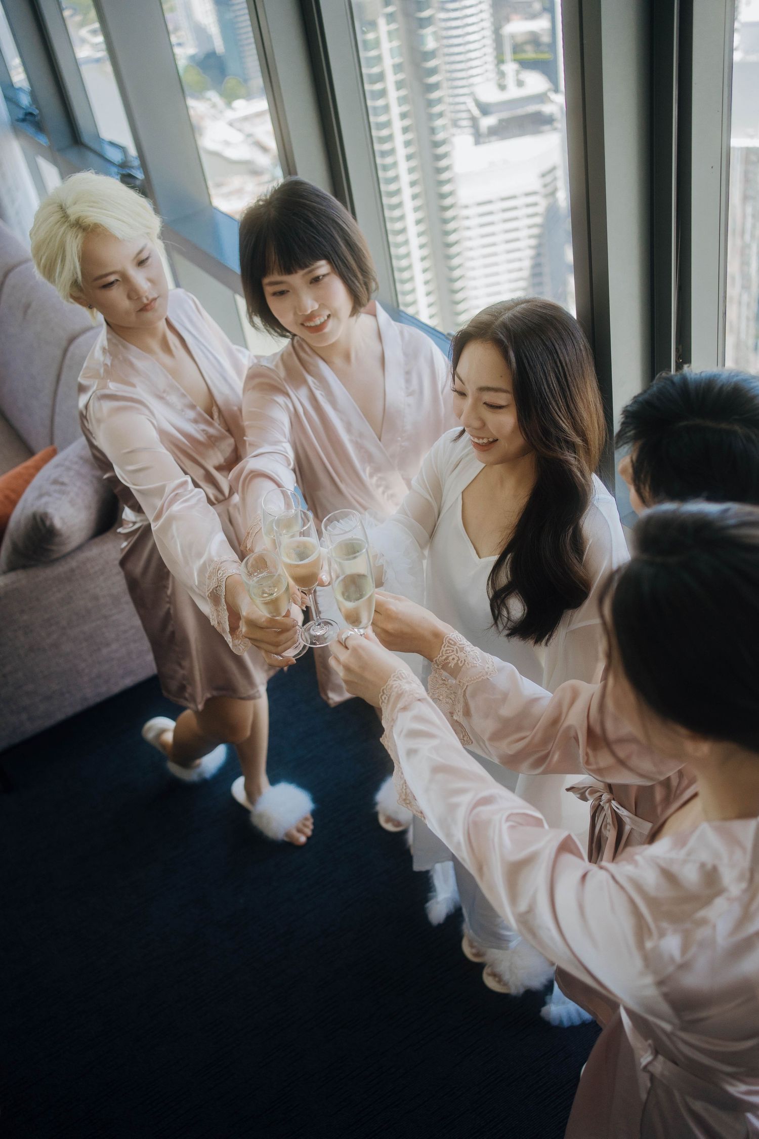 A group in pink silk robes sharing champagne and laughter during a celebration.
