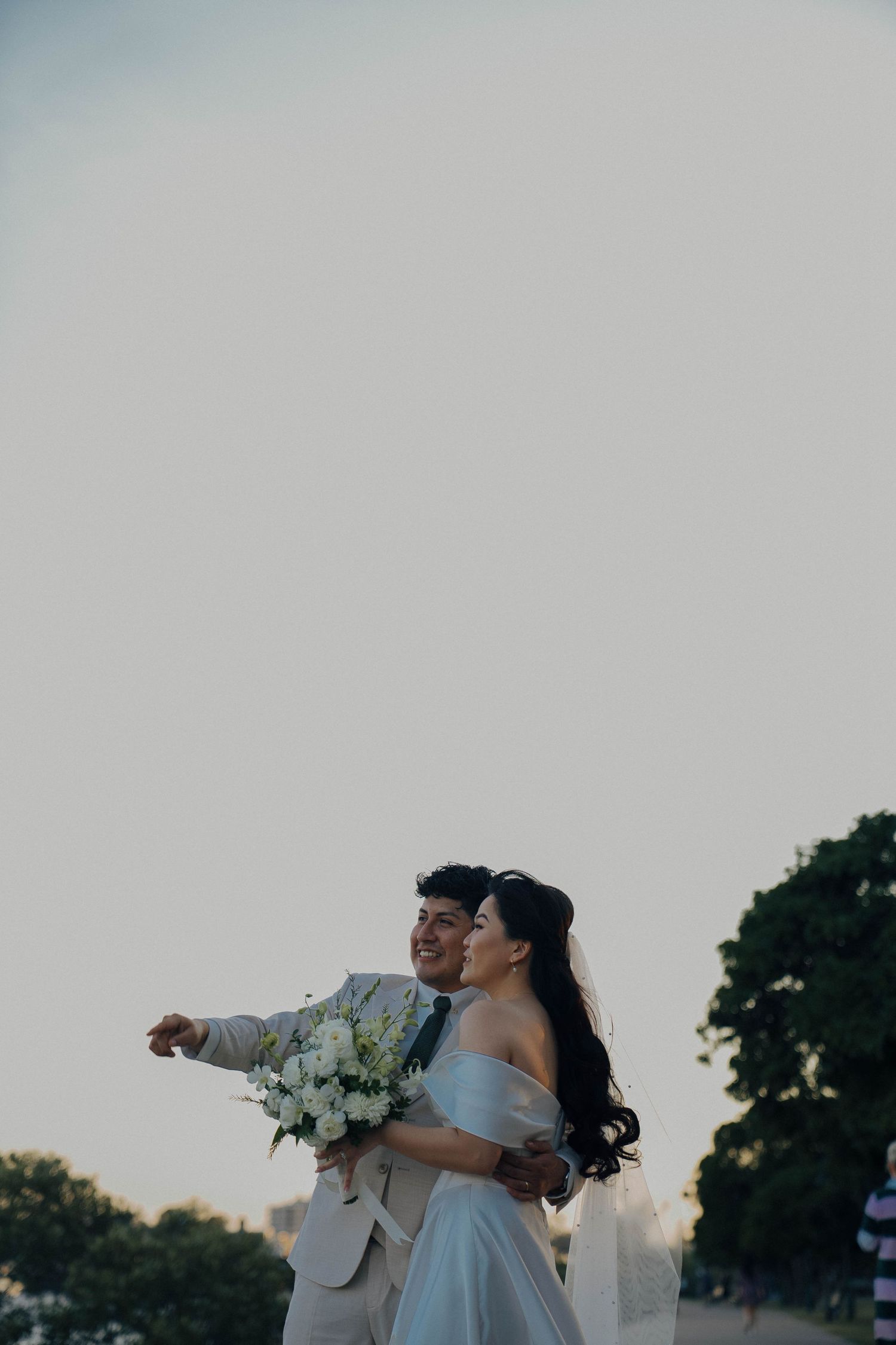 Newlywed couple dances together at sunset in an outdoor celebration.