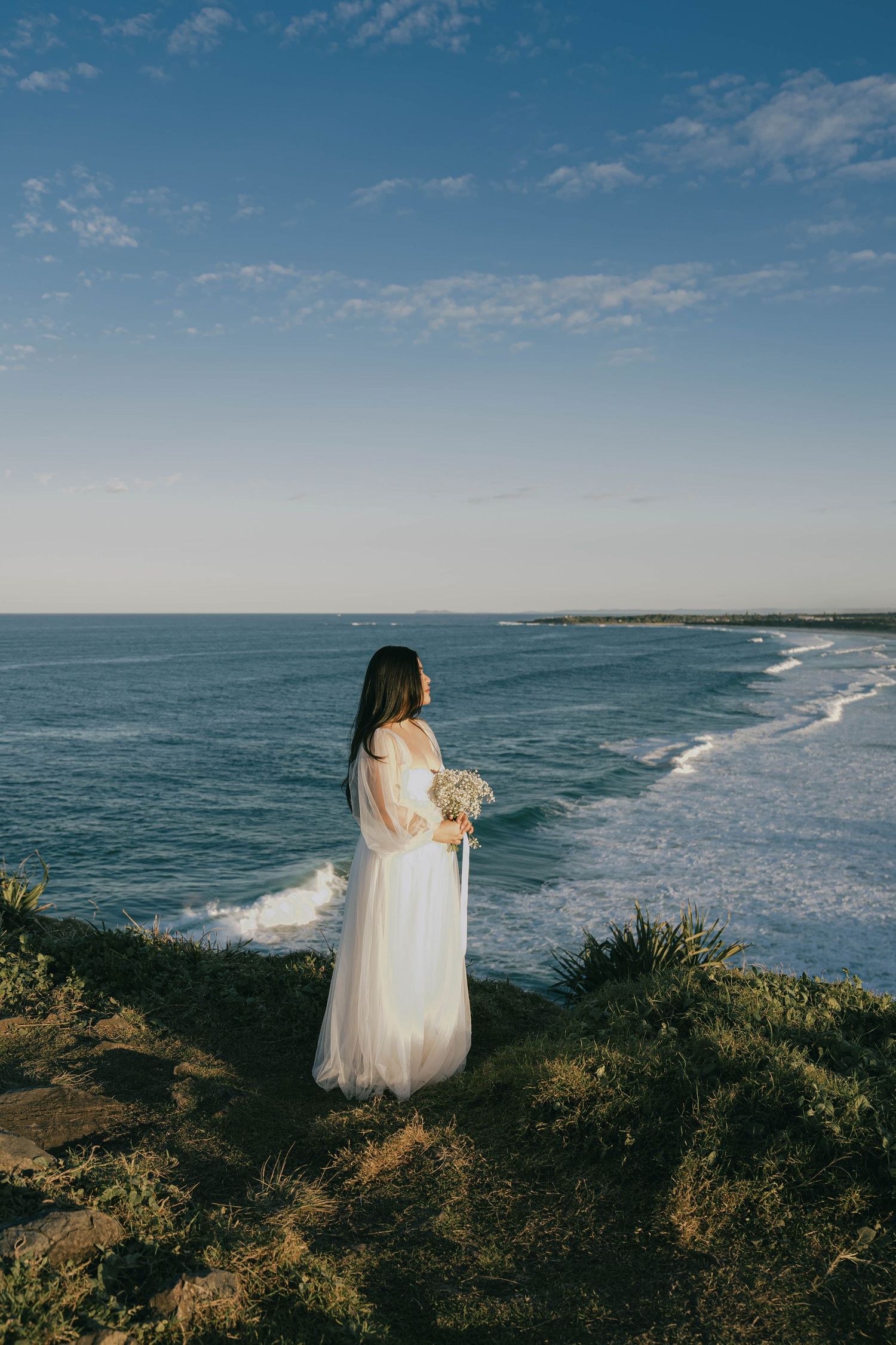 Scenic coastal landscape view with ocean waves crashing against the shoreline under a bright blue sky.