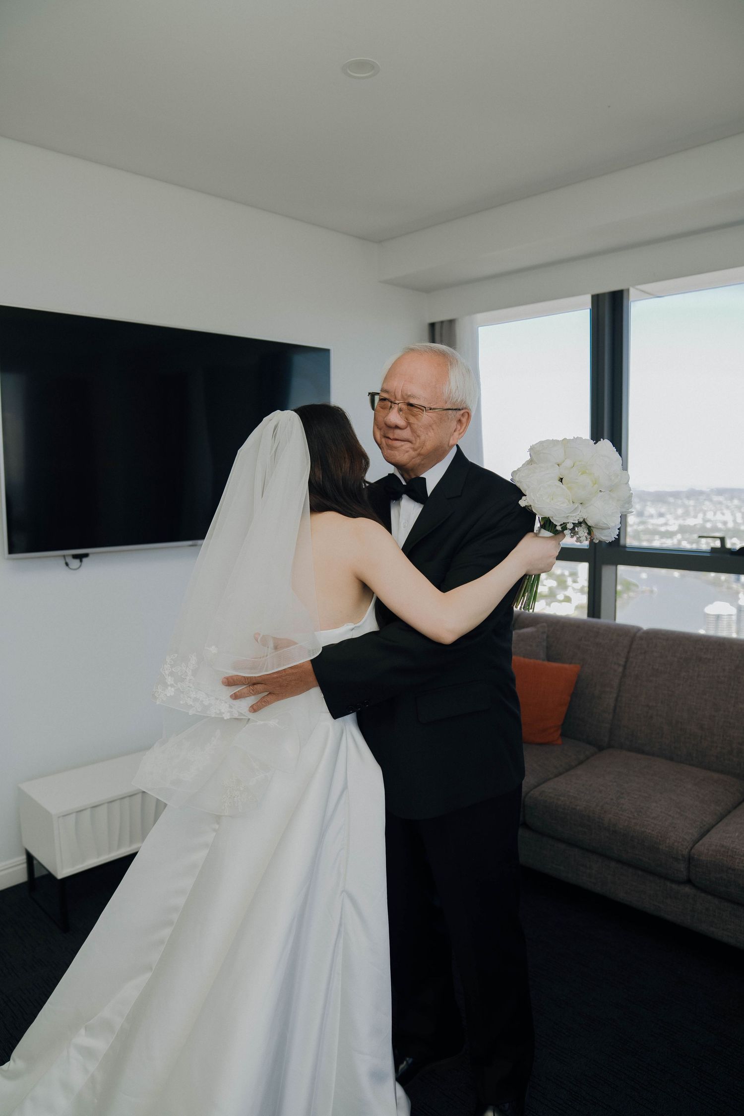 A tender first look moment between two people, with one wearing a flowing white wedding dress in a modern room.