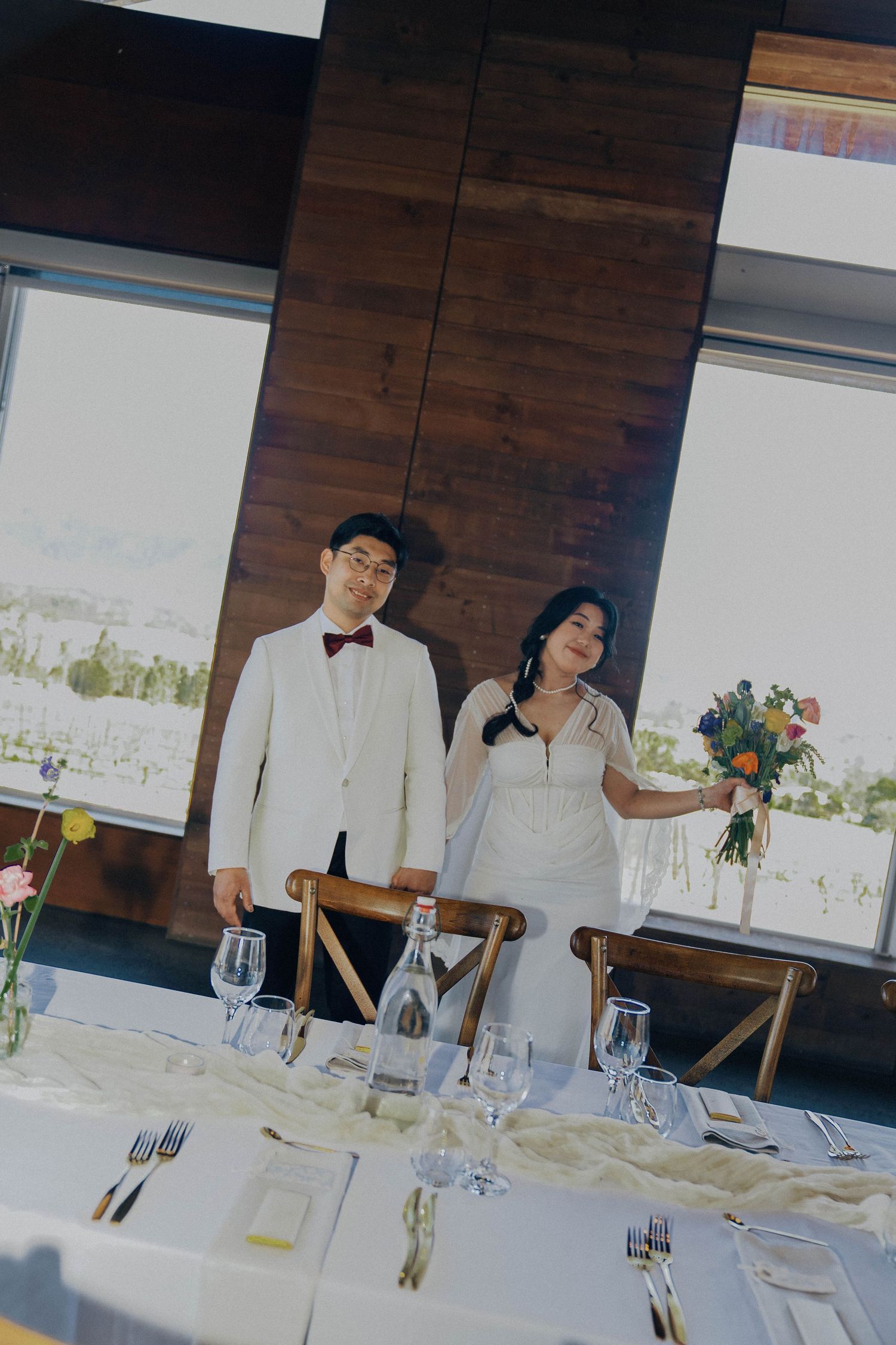 Elegant wedding reception table settings with white linens, glassware and floral centerpieces in a modern venue.