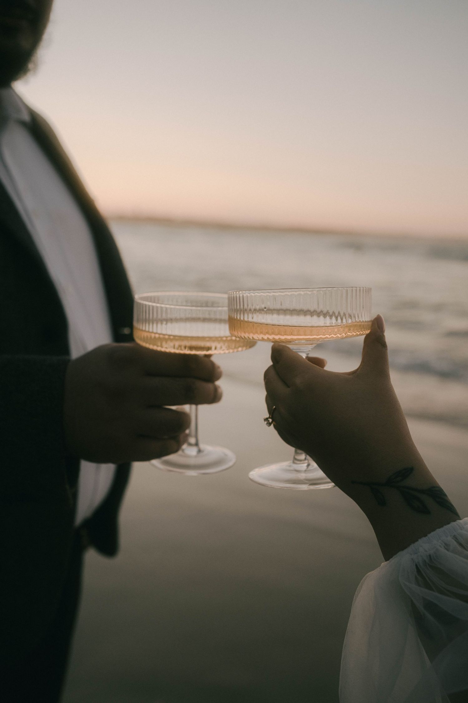 Hands holding wine glasses against a sunset ocean backdrop in a sequence of silhouetted images.