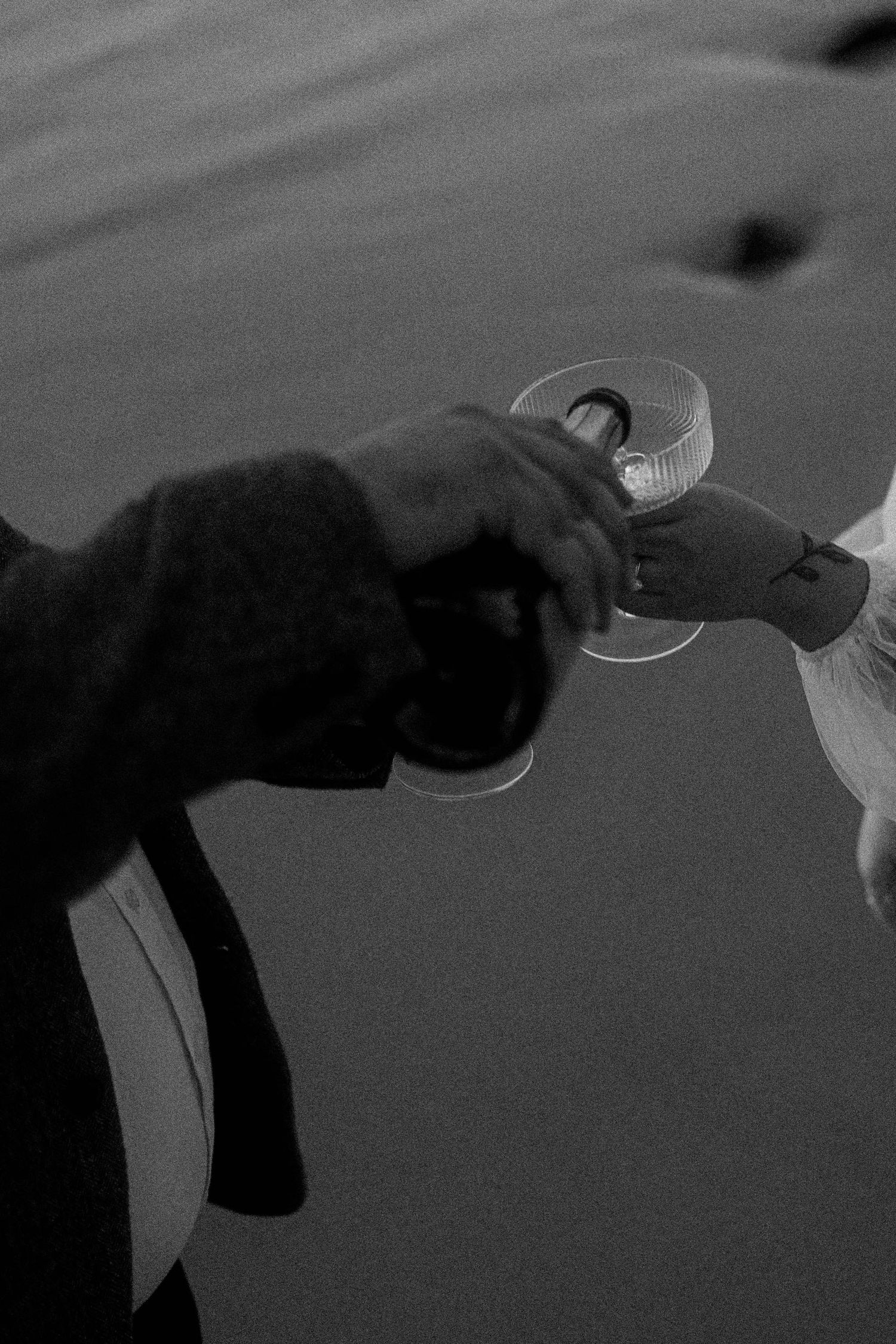 A series of black and white images showing hands holding and pouring a drink in a dramatic lighting setup.