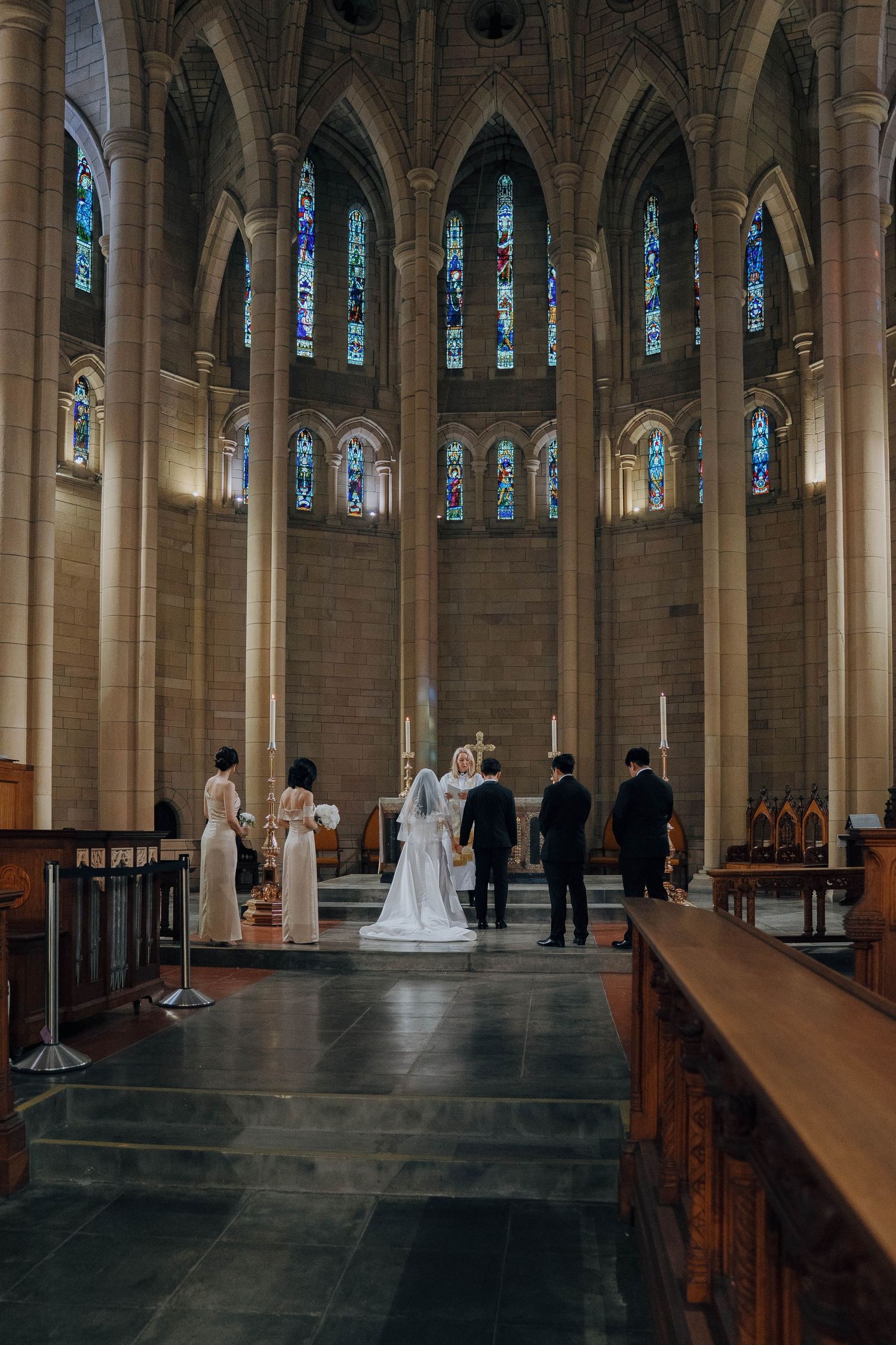 Interior panorama of a Gothic cathedral with tall columns, stained glass windows, and wooden pews lining the nave.