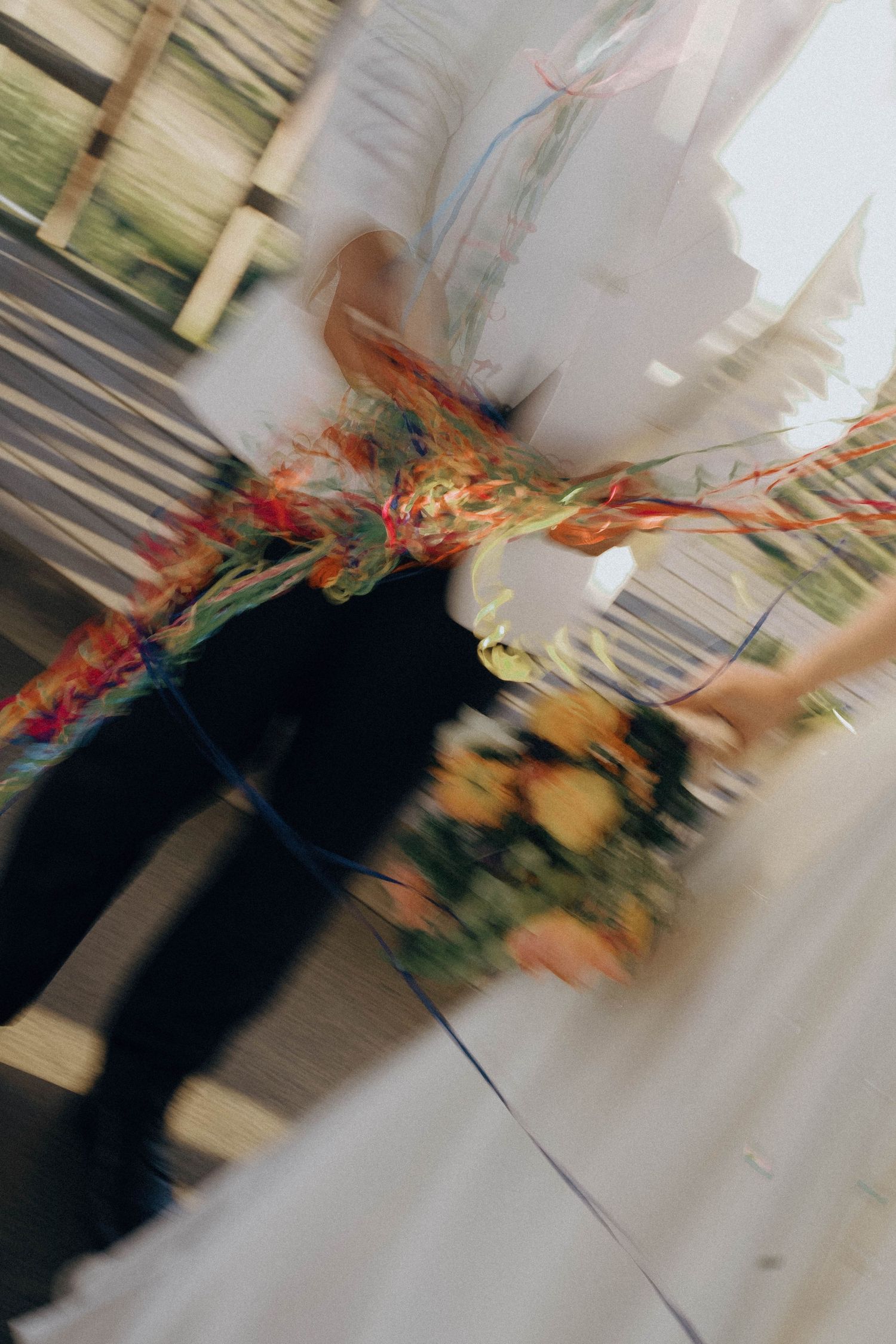 Motion-blurred sequence of wedding couple walking with vibrant autumn floral bouquet and white dress against light background.