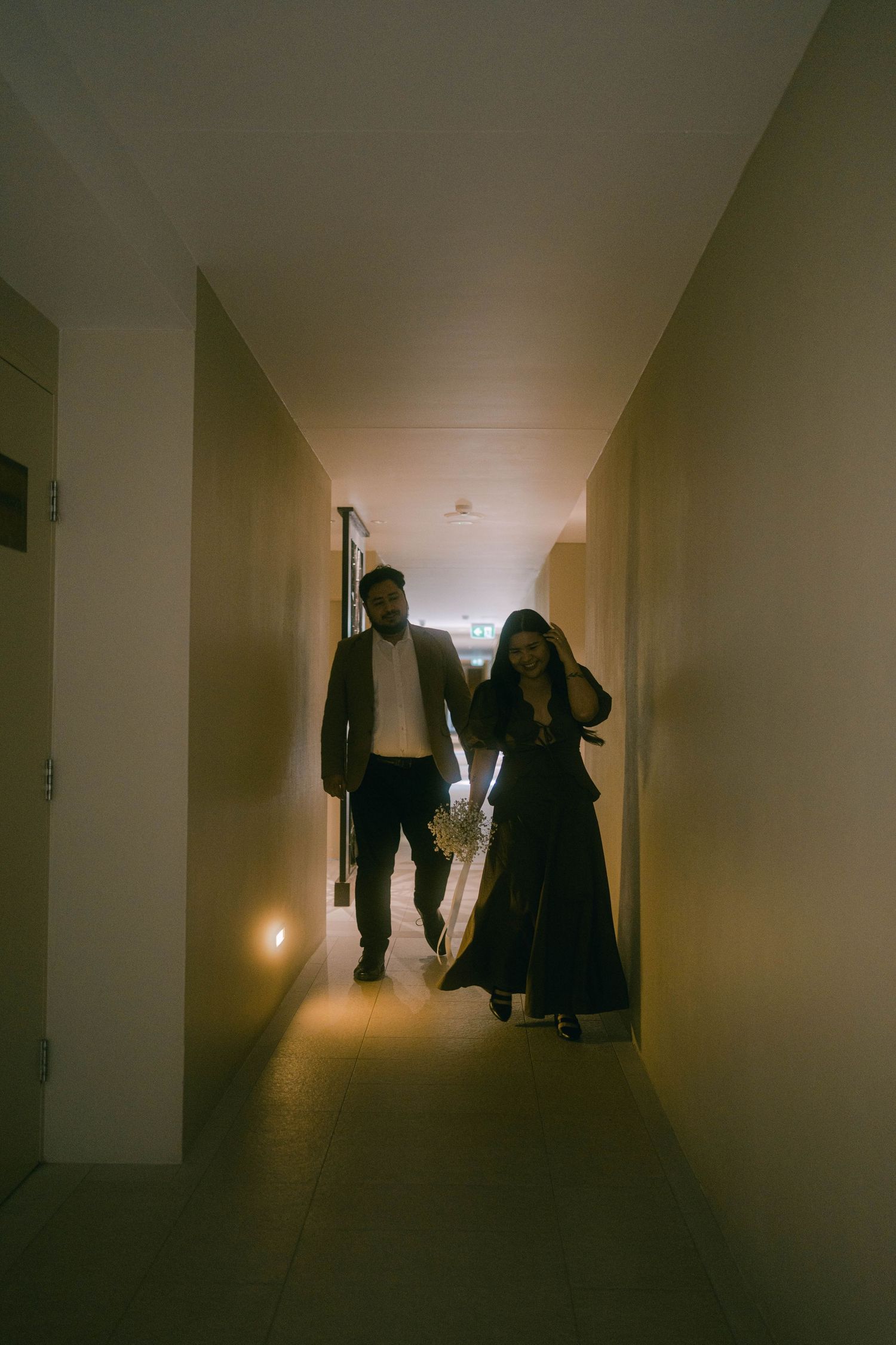 Dark and moody hallway with silhouetted figures walking in dim lighting creating an eerie atmosphere.