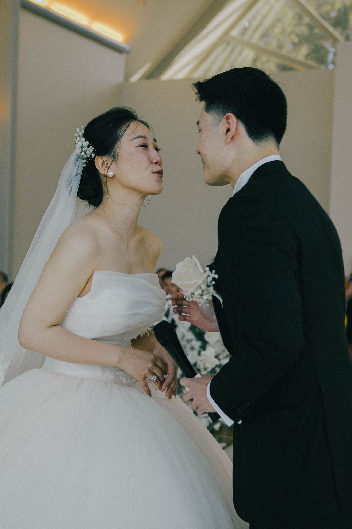 A romantic wedding scene shows a couple in traditional white dress and black suit sharing an intimate moment during their ceremony.