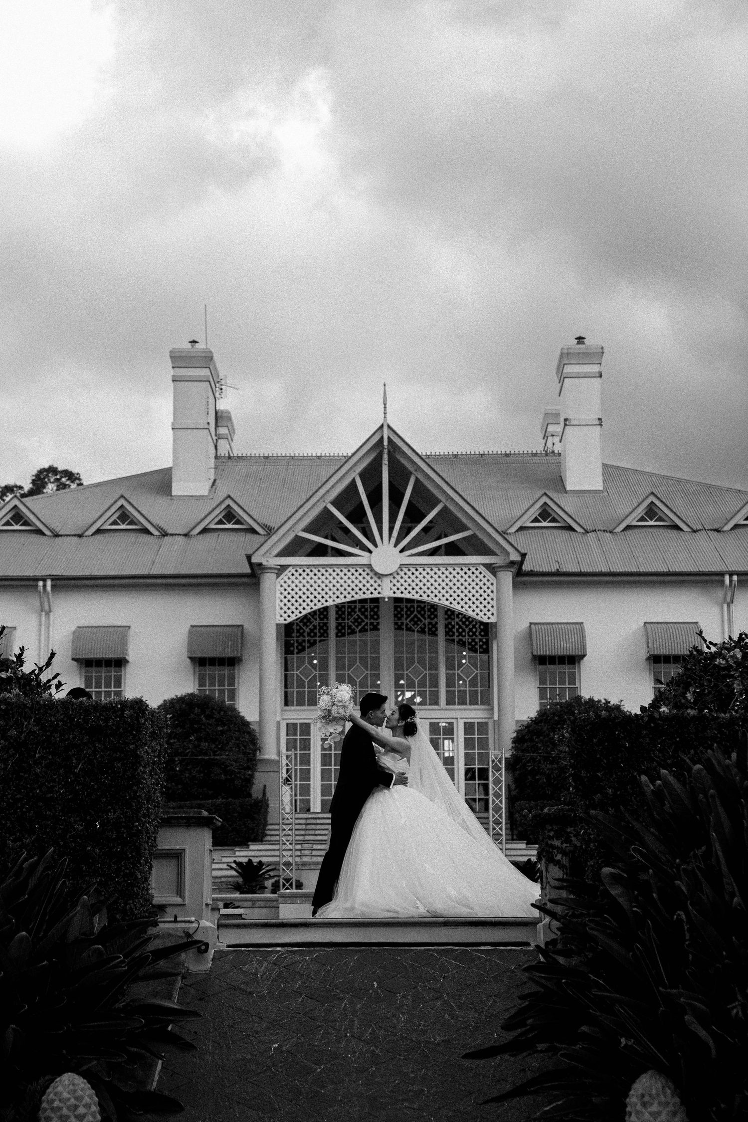 A black and white photo series showing a wedding dress silhouette against a vintage house exterior with cloudy skies.
