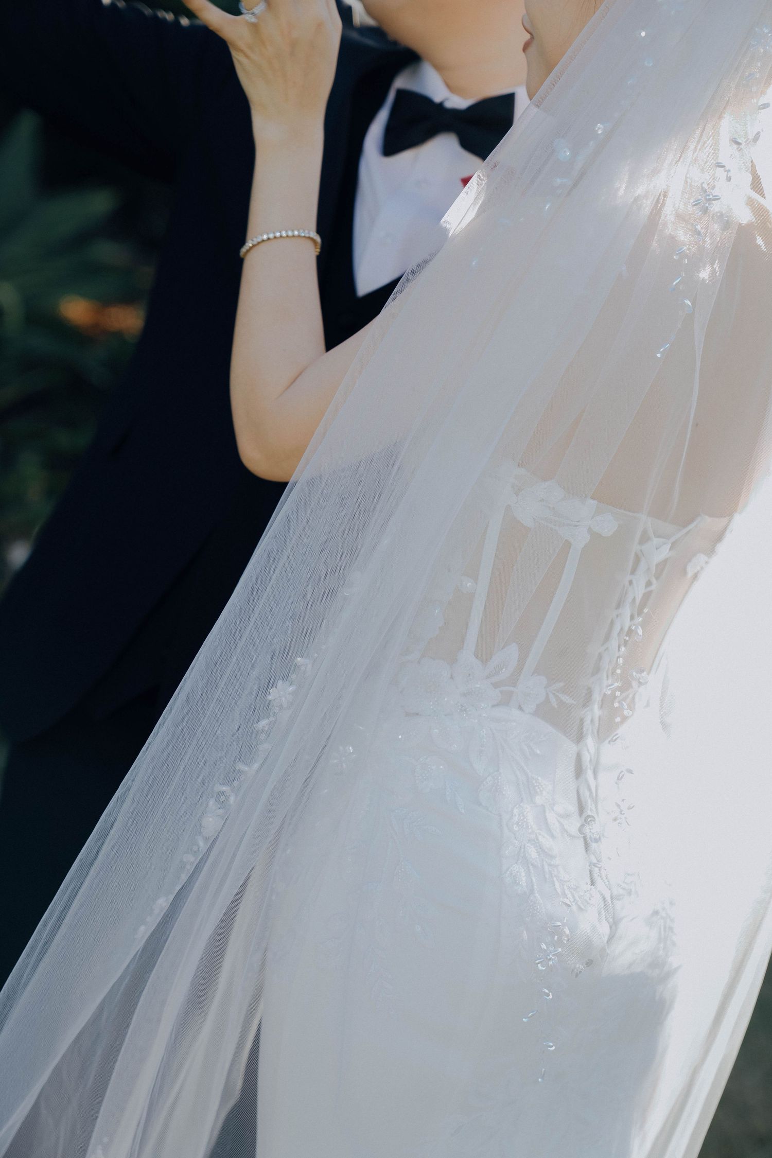 Close-up details of a white lace wedding dress with delicate embroidery and flowing tulle fabric.