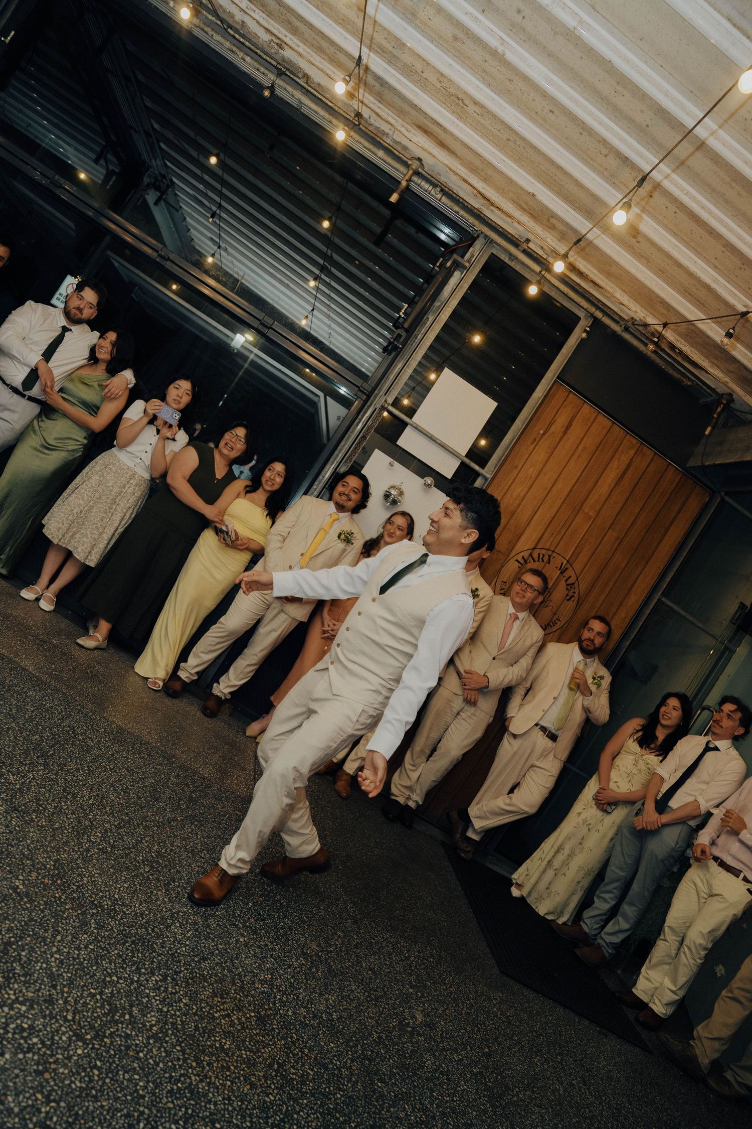 A sequence of candid moments at an indoor event showing people in beige and cream colored outfits interacting in a hallway.