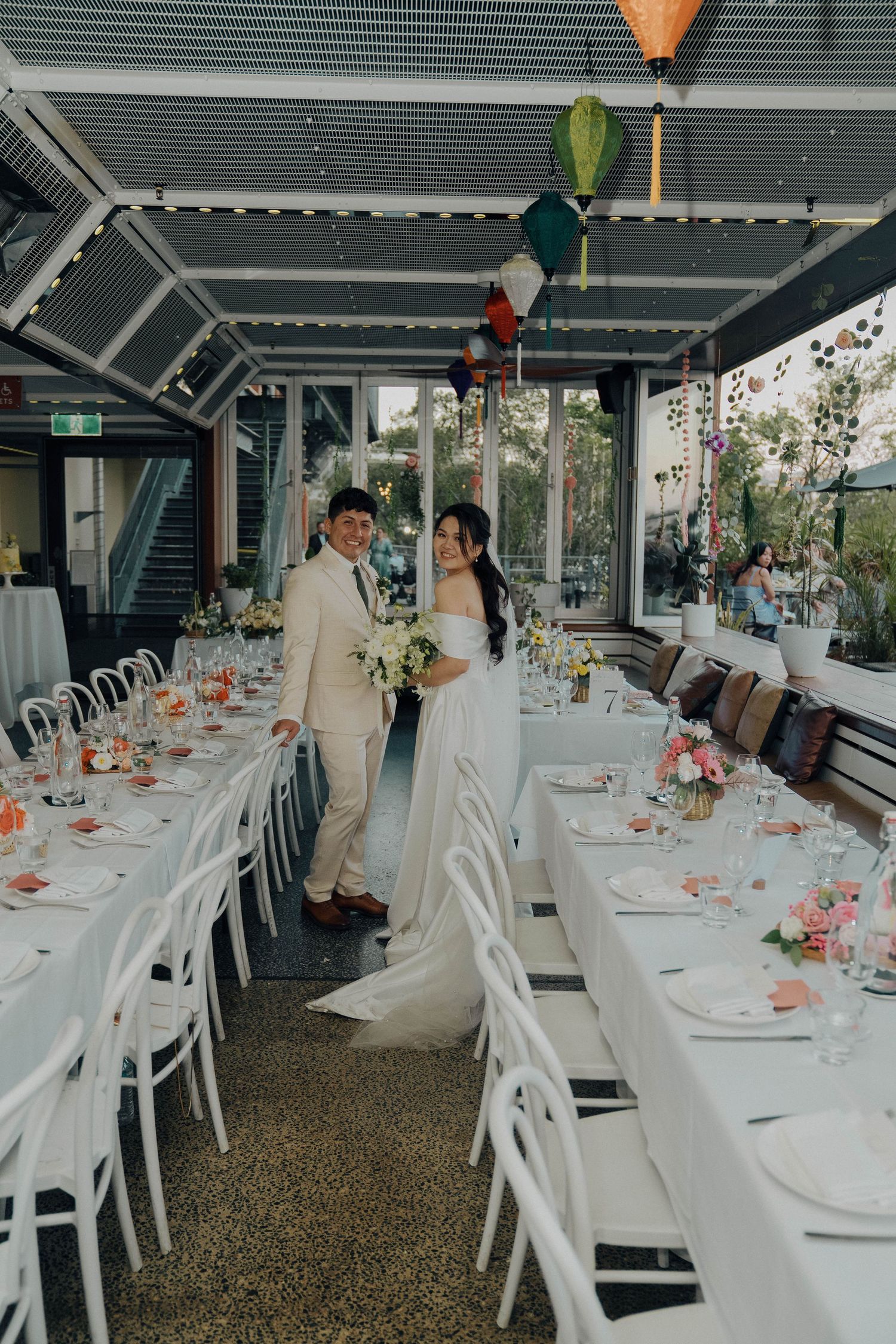 Wedding reception tables set with white linens and colorful floral centerpieces in an elegant covered outdoor venue.