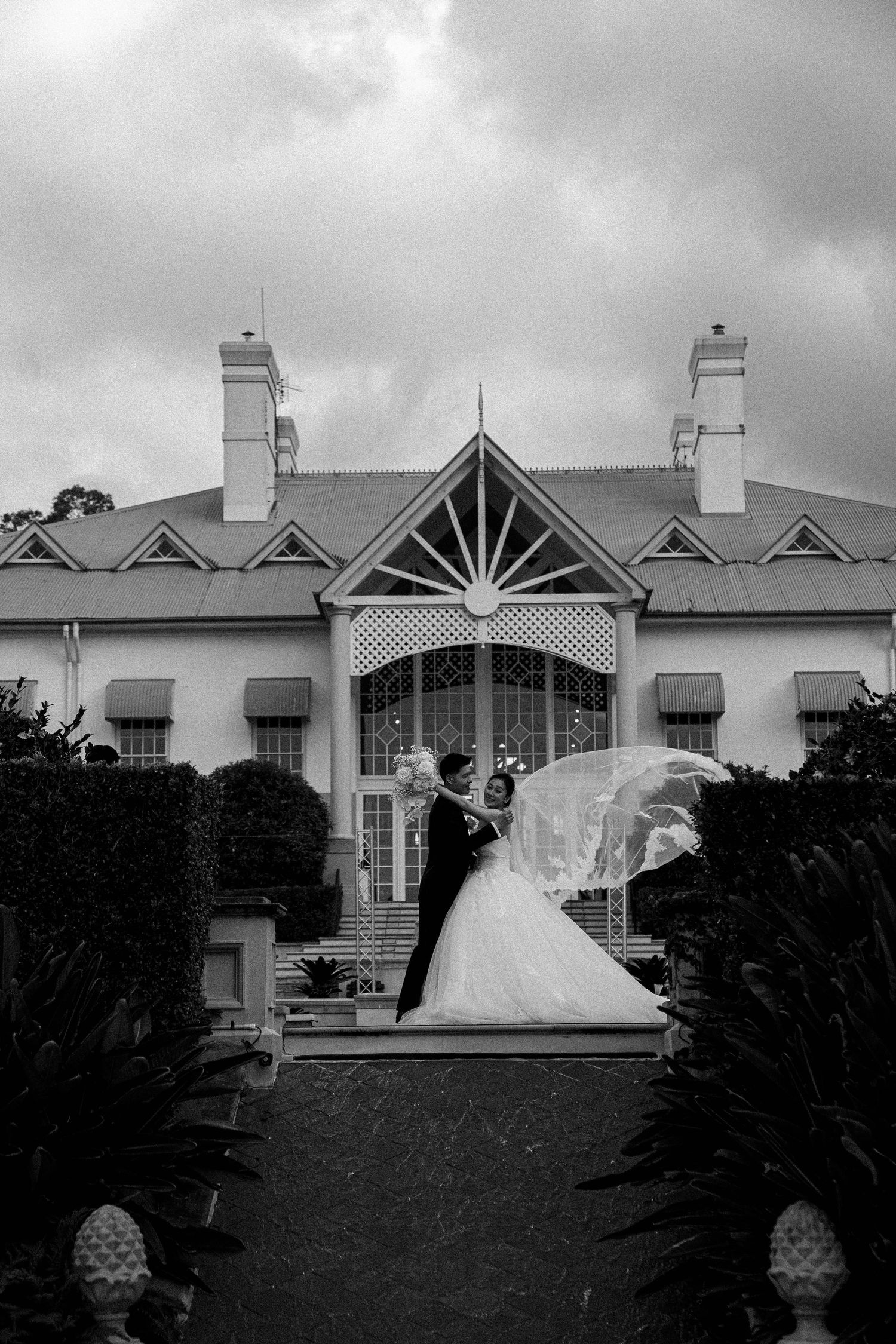 A dramatic black and white sequence showing a wedding dress billowing in the wind against a stately building backdrop.