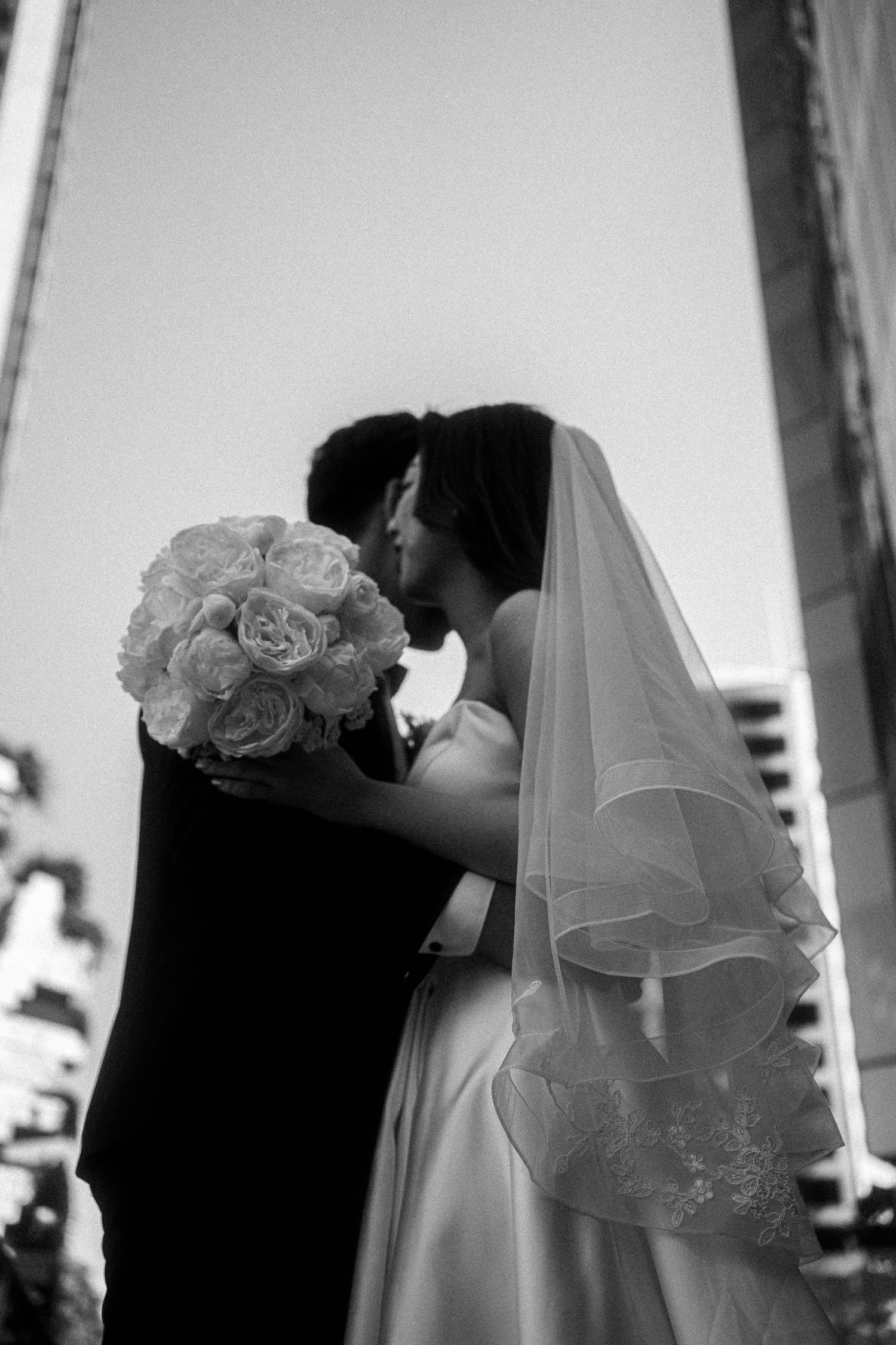 A romantic black and white wedding photo series showing a couple embracing in four sequential frames.