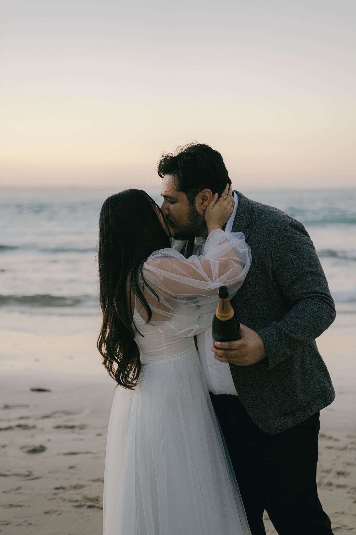 A romantic couple shares intimate moments on a beach at sunset in a series of connected photos.