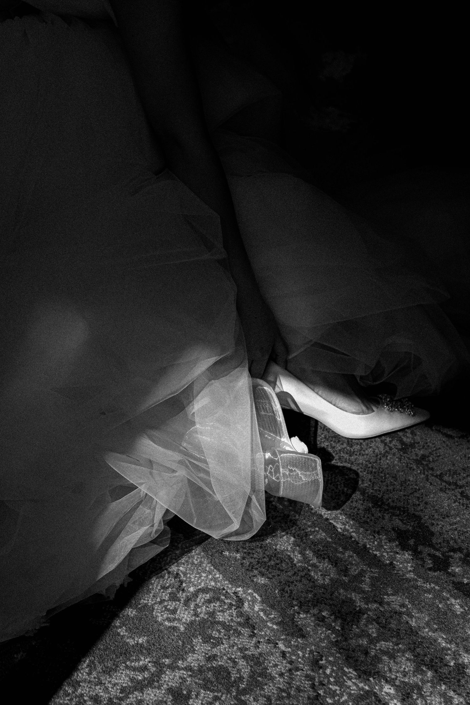 A close-up view of sheer white fabric or veil material draped over a textured dark surface in dramatic lighting.
