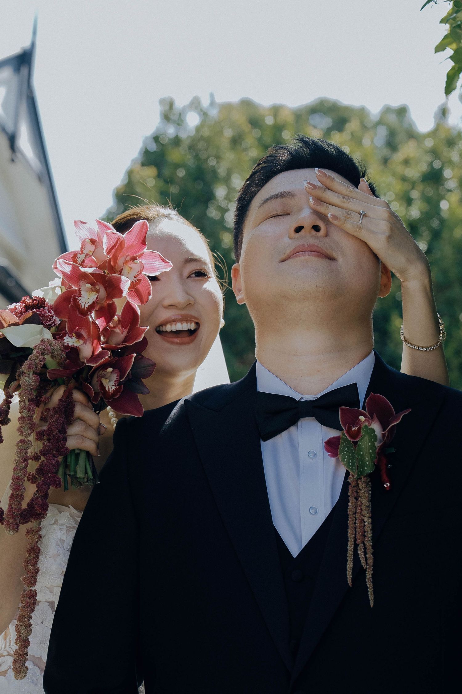 A couple in formal wedding attire poses playfully with pink flowers in a series of candid outdoor photos.