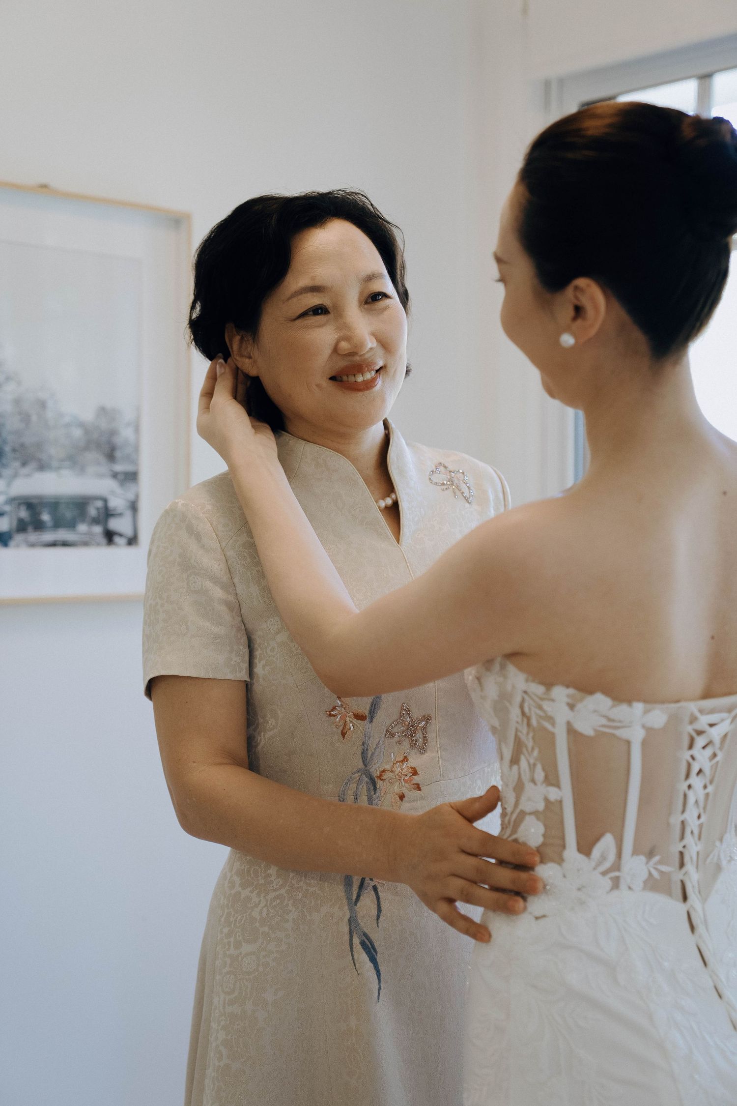A tender moment captured during a wedding dress fitting as two people share an intimate conversation in a bridal boutique.
