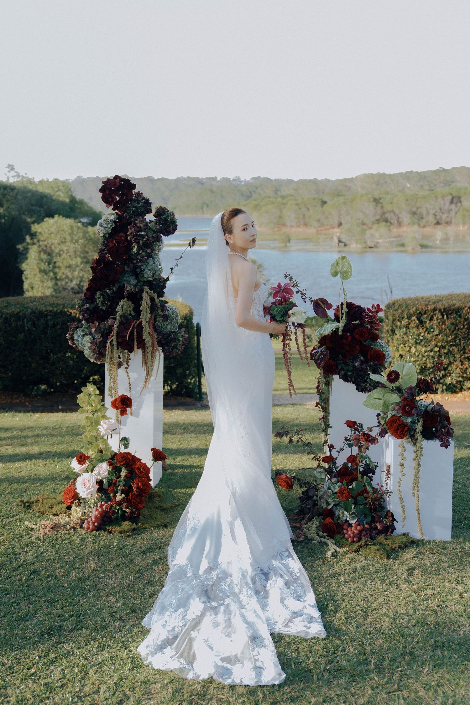Elegant white wedding dress with lace details photographed from multiple angles against a lakeside outdoor setting.