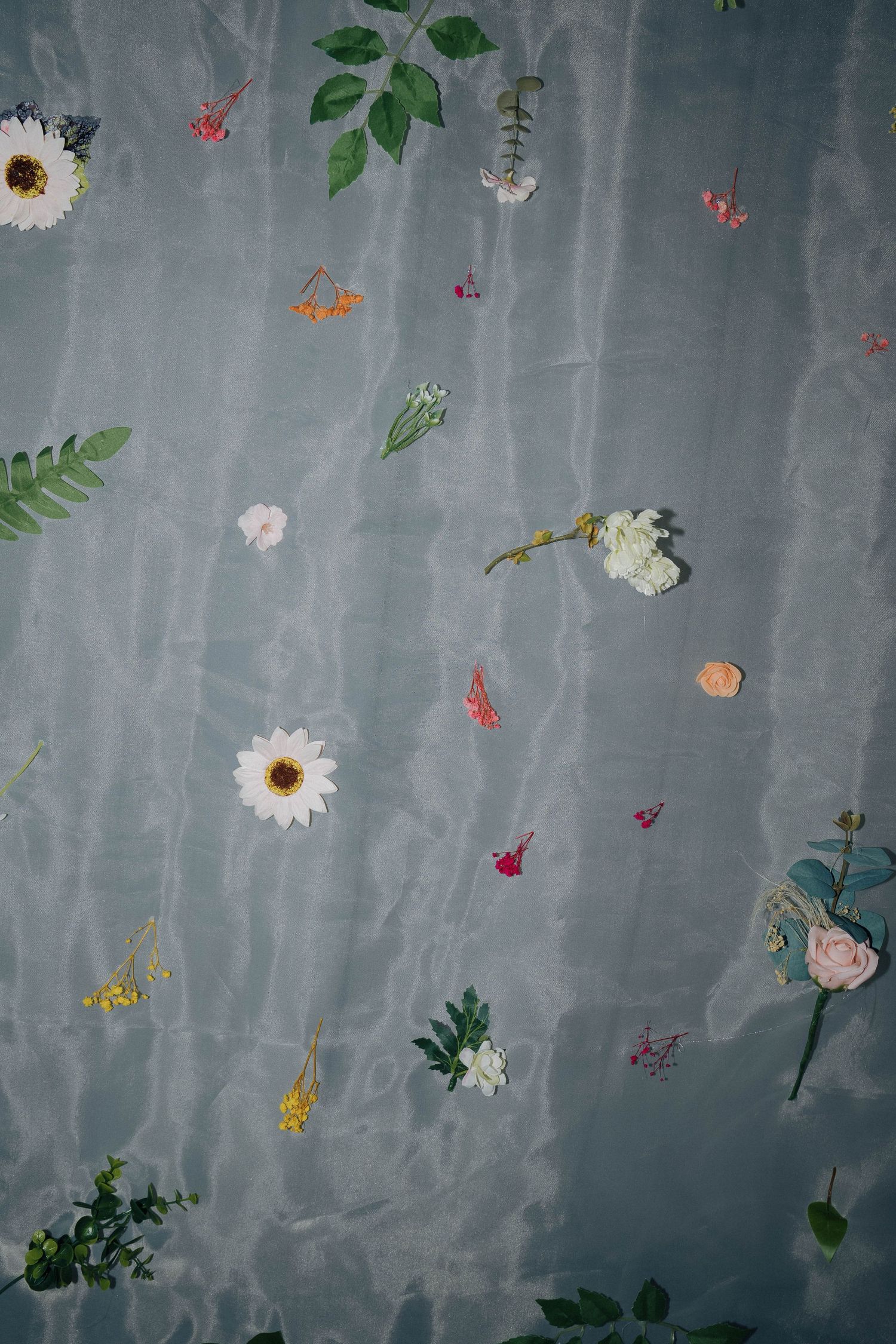 Delicate flowers and leaves scattered across a sheer grey fabric create an ethereal, romantic pattern.