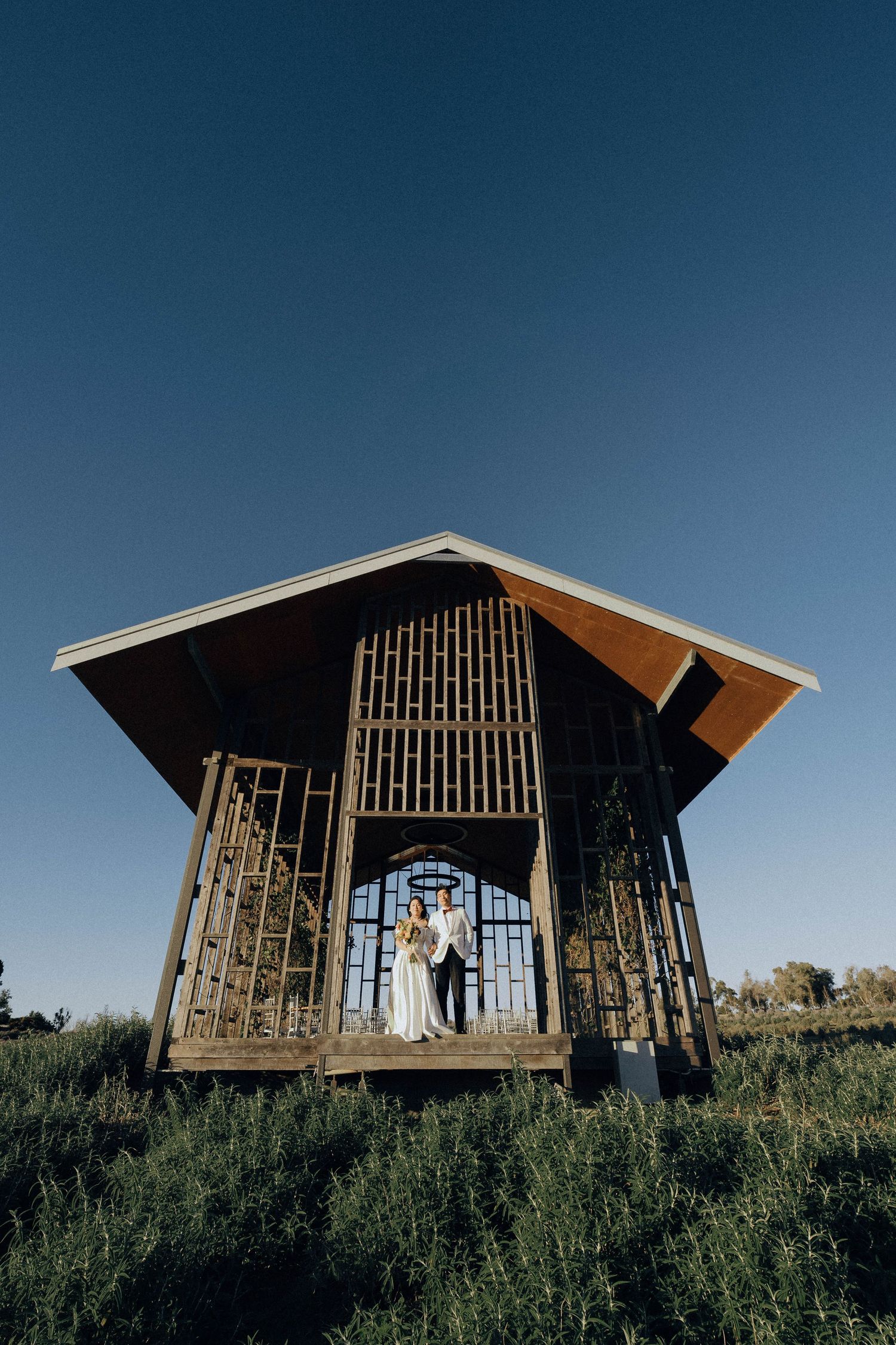 Modern wooden cabin with slatted walls photographed from different angles against a blue sky in a grassy field.