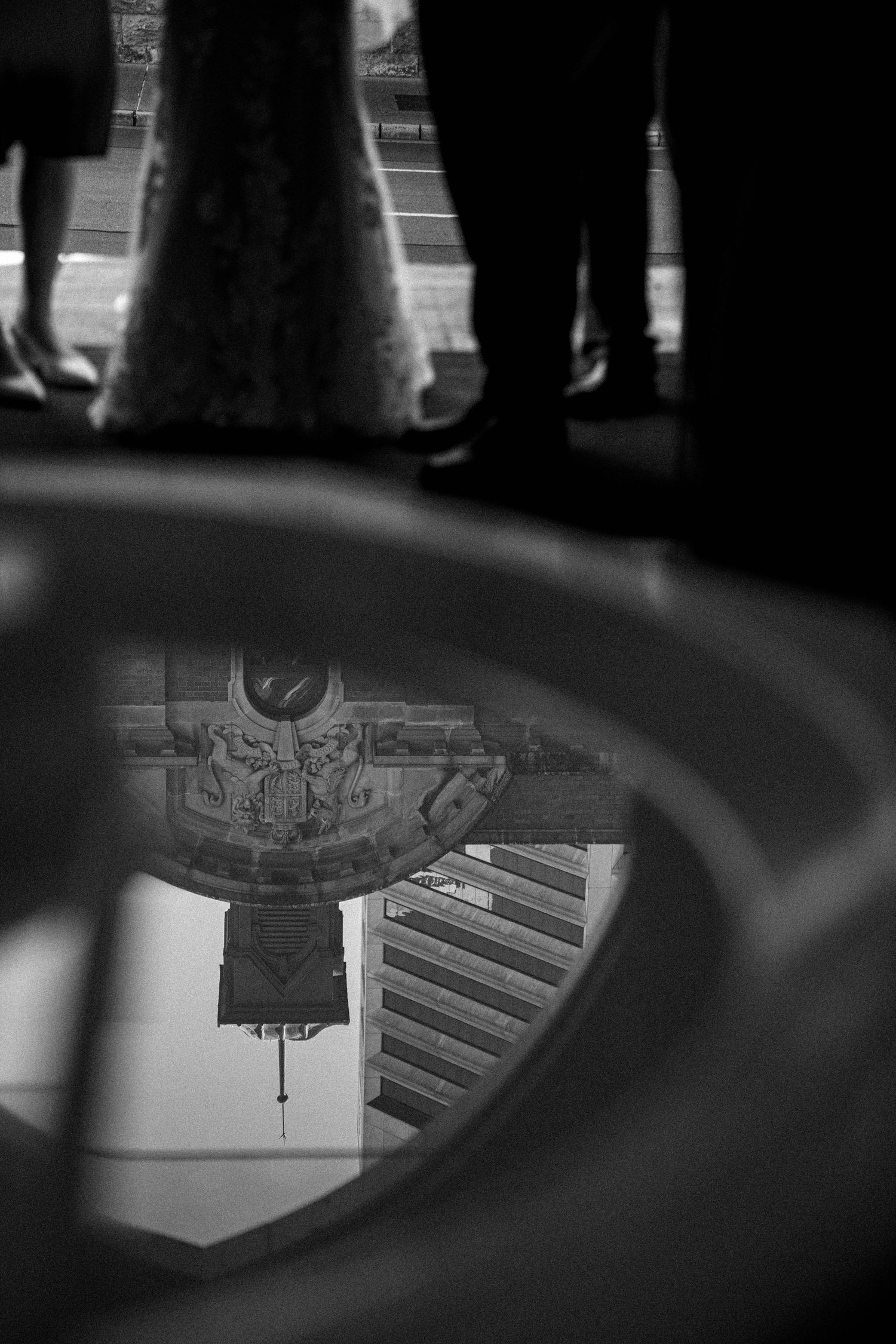 Artistic black and white photograph showing a street art reflection in a car side mirror.