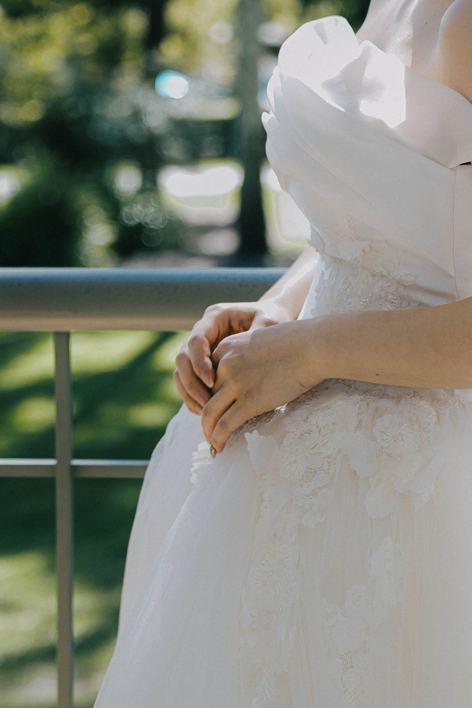 Close-up view of a white wedding dress with delicate details and fabric texture in natural outdoor lighting.