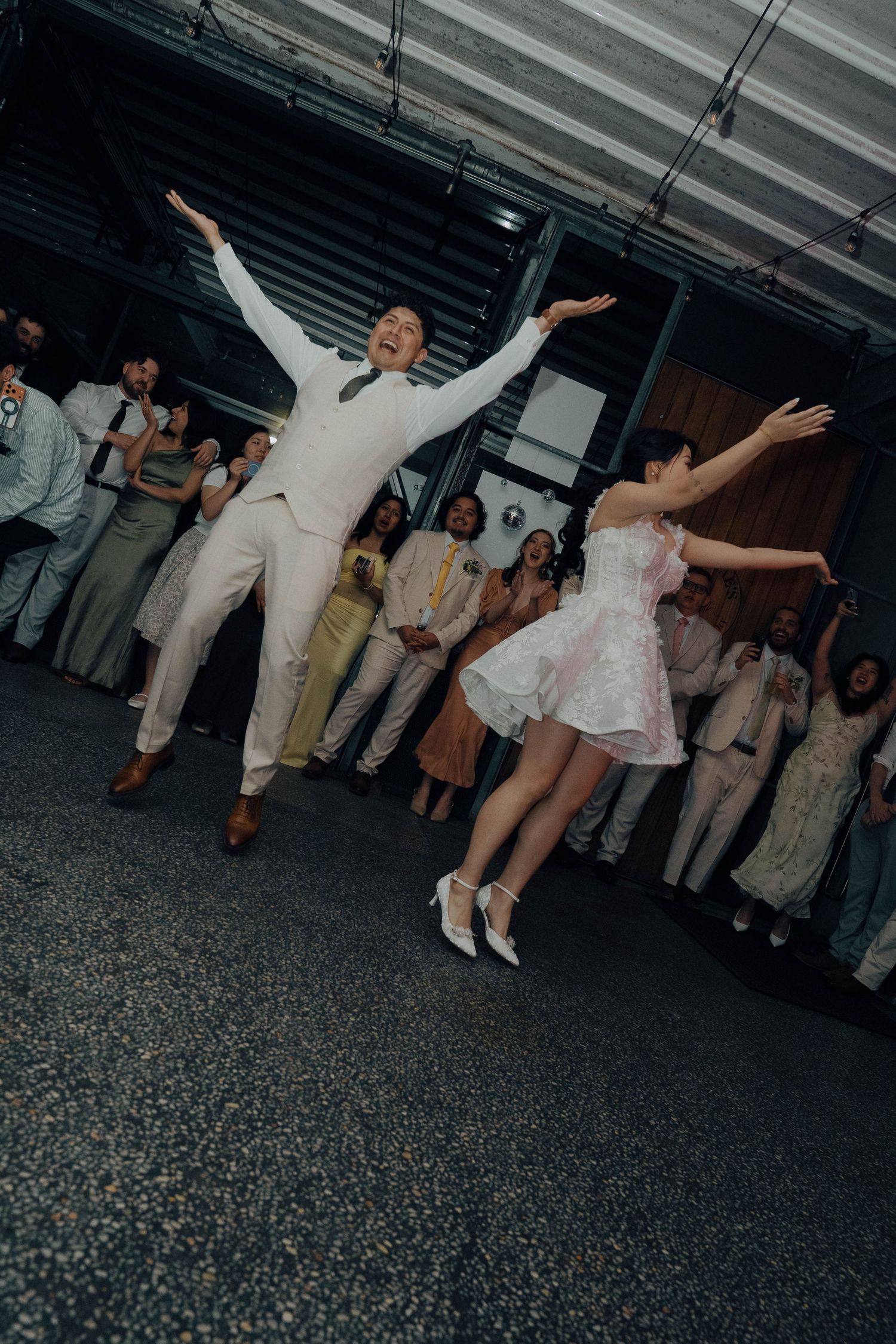 A group of party guests dancing and posing with their arms outstretched in a dimly lit venue.