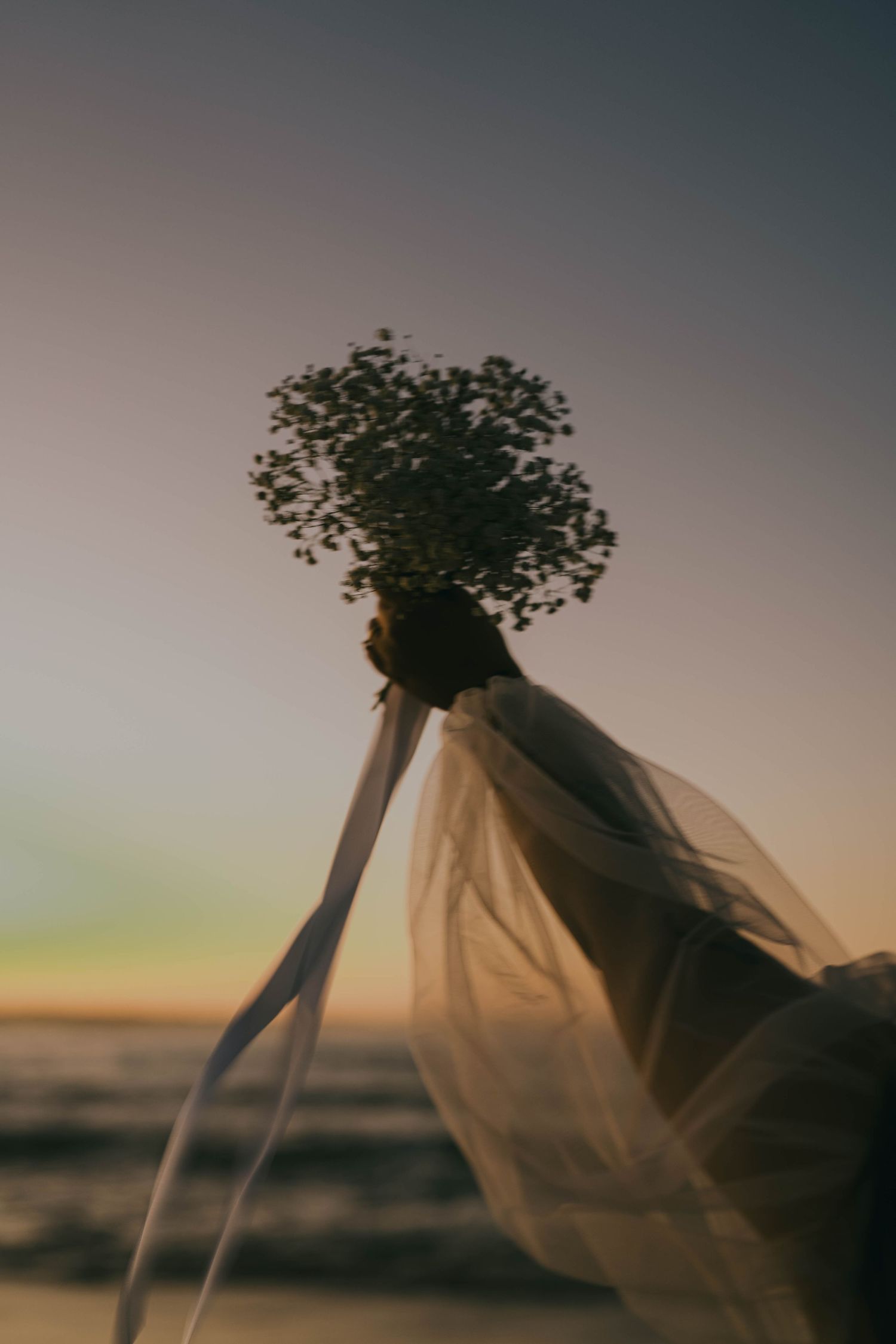 A sequence of photos showing a sheer veil blowing in the wind against a sunset sky with dried flowers on top.