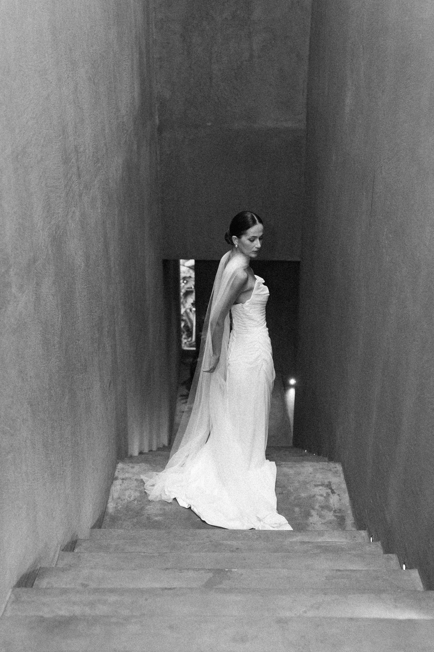 A sequence of black and white photos showing a bride in a flowing white dress and veil walking down a dark corridor.