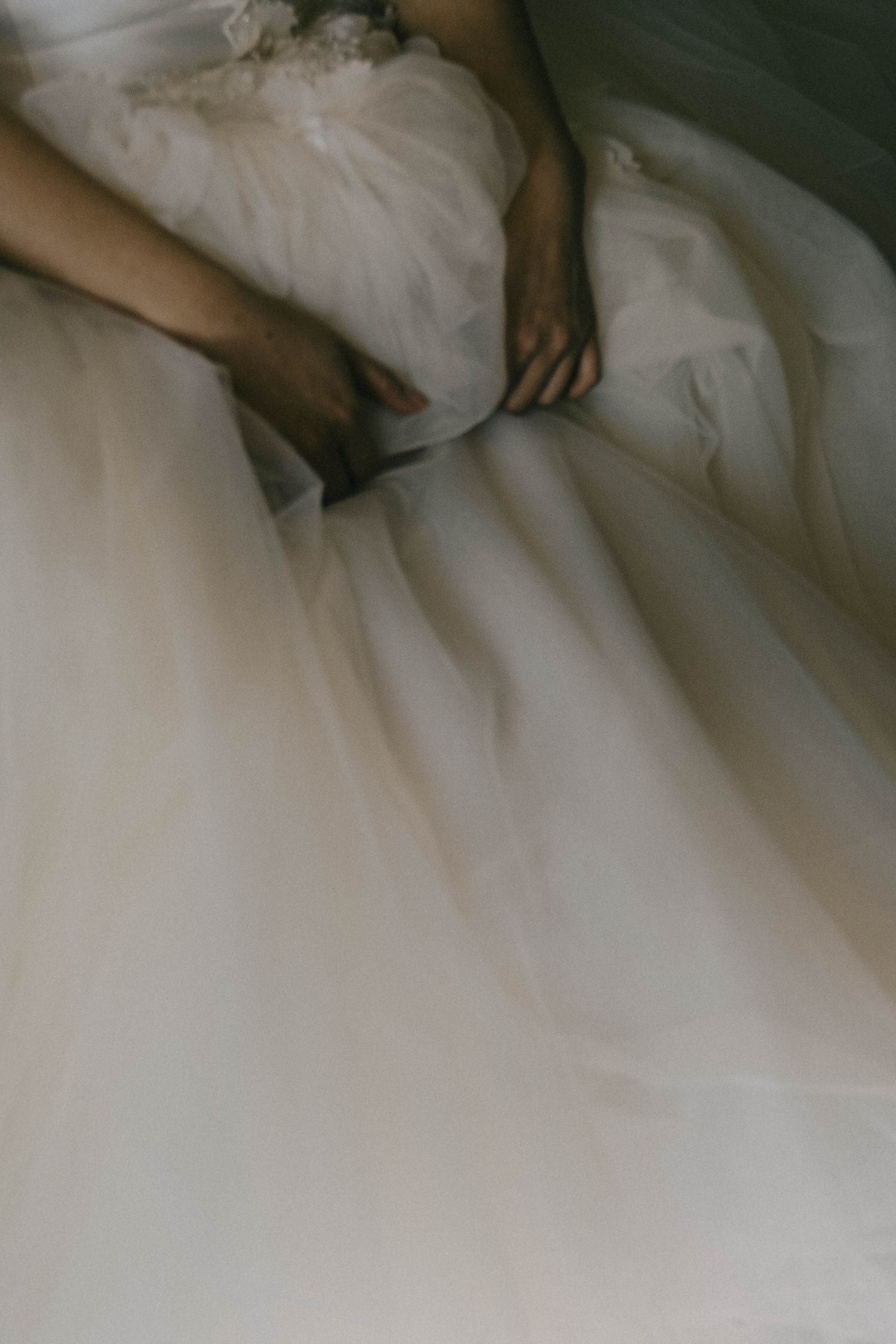 Close-up view of white wedding dress fabric with delicate pleats and folds creating elegant texture.