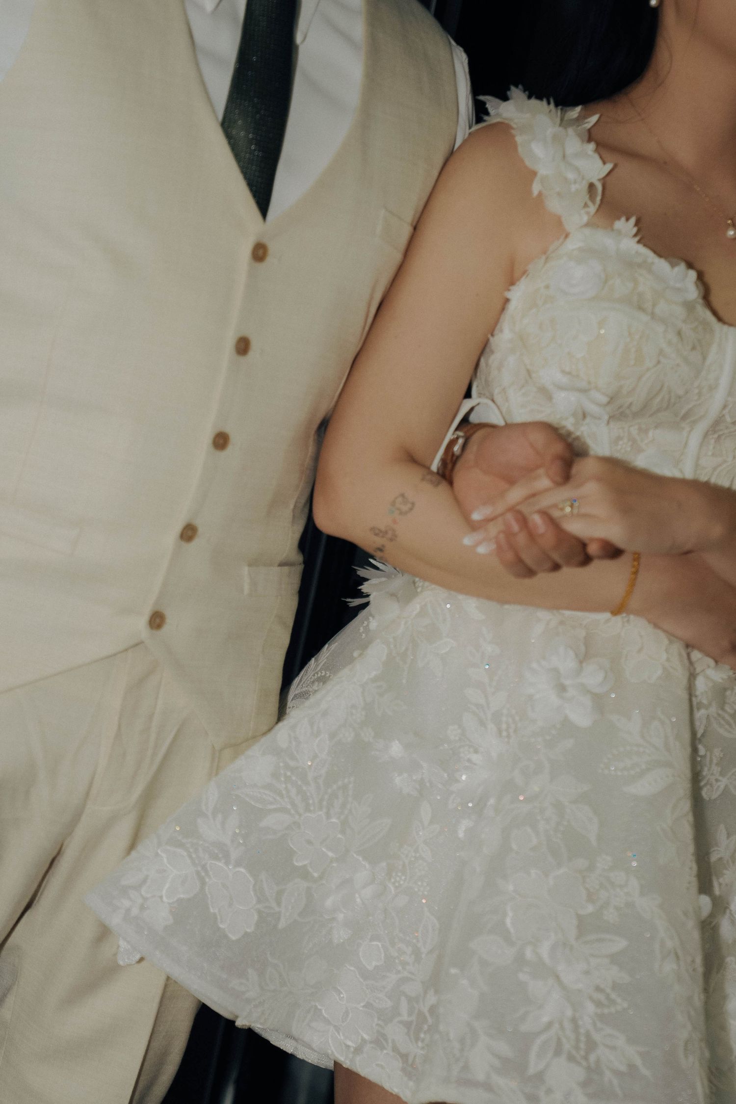 Close-up view of white wedding dress details showing delicate lace and ruffles against a light background.