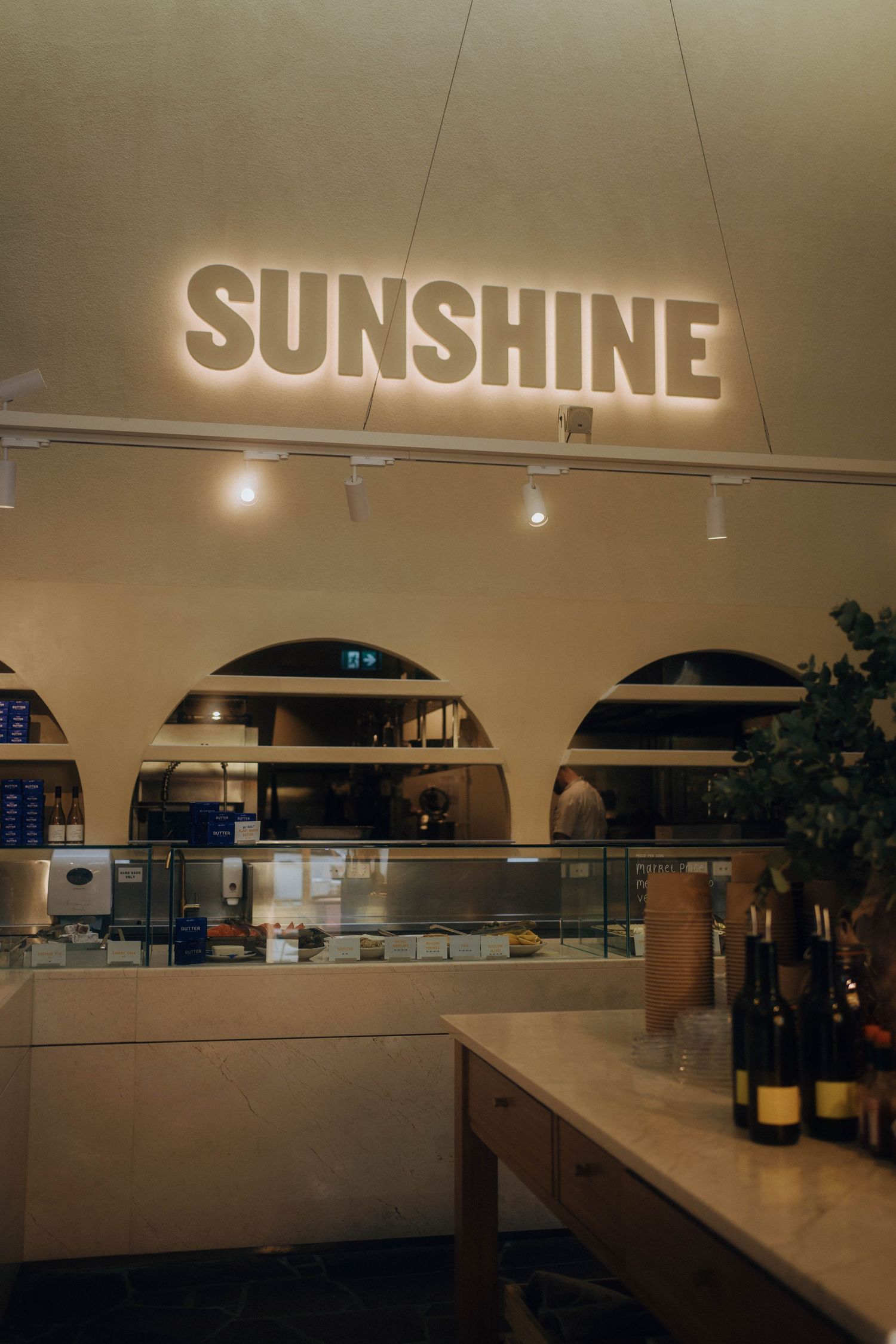 A dimly lit commercial space with 'SUNSHINE' signage and illuminated display cases along a curved wall.