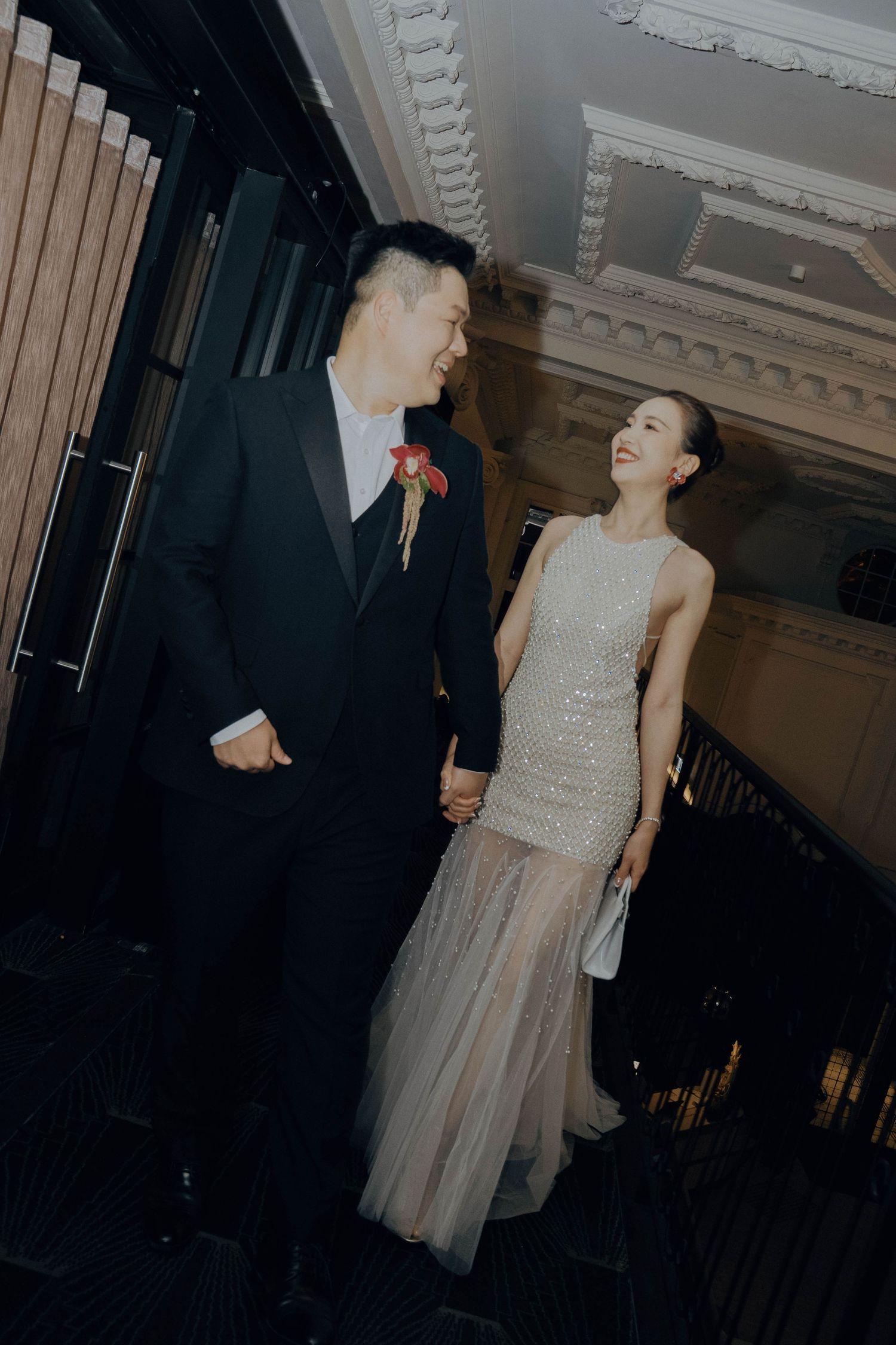 A couple dancing together at an elegant indoor venue with ornate white crown molding on the ceiling.