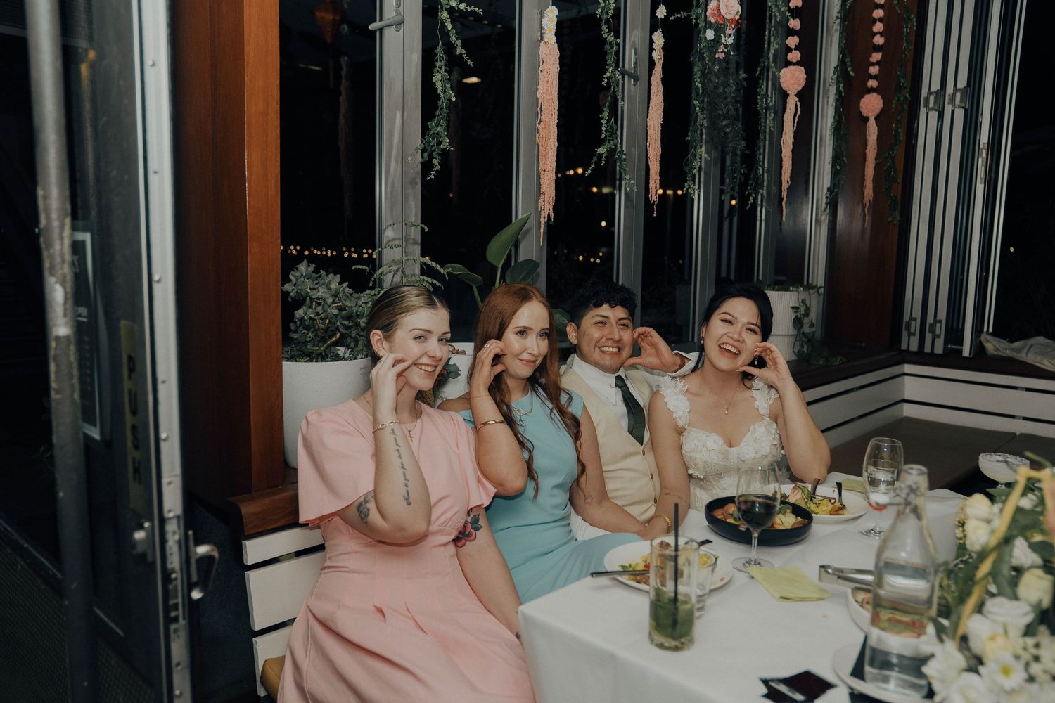 A group of friends laughing and enjoying drinks together at a restaurant table.