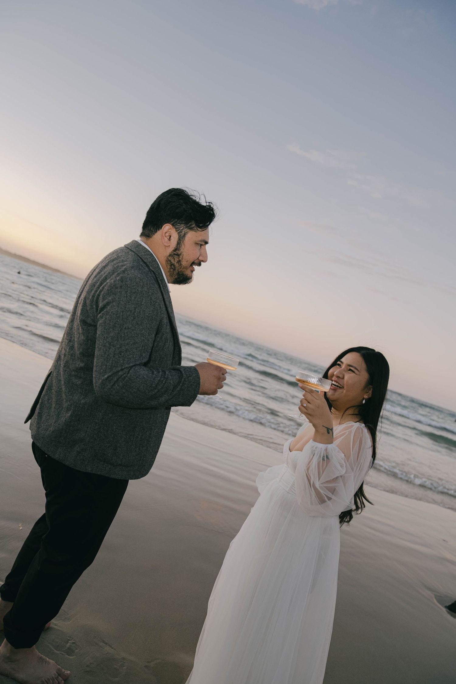 A couple shares a romantic moment at sunset on a beach as they dance together in a series of candid photos.